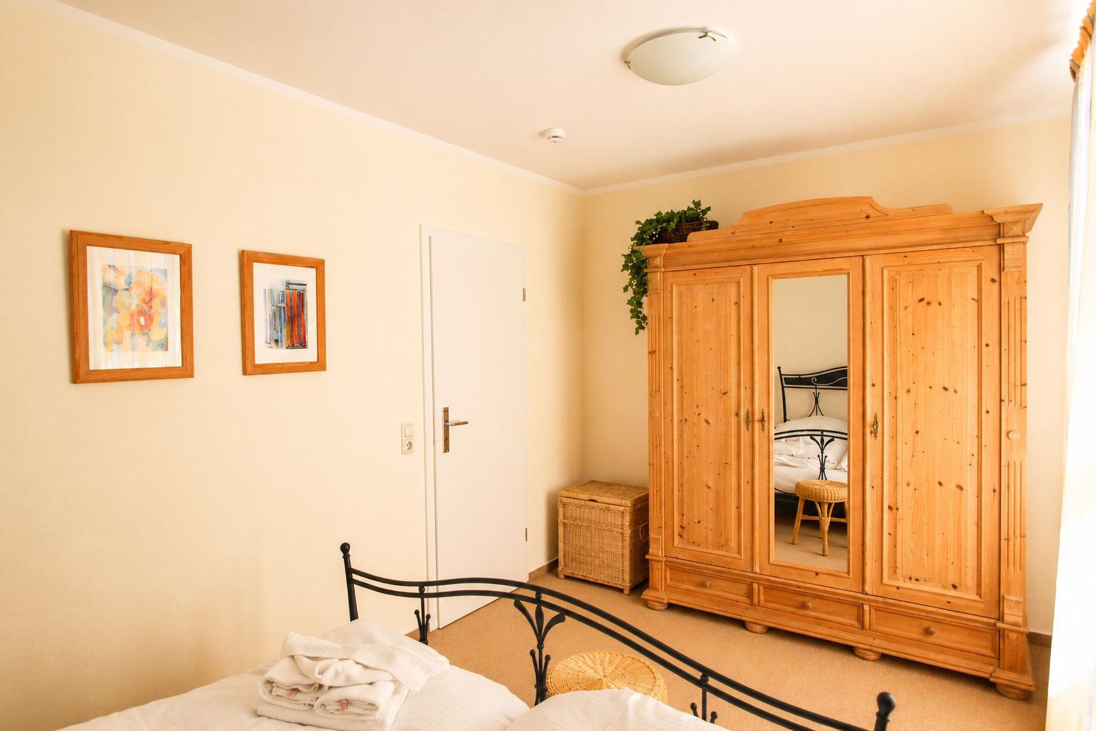 Schlafzimmer mit Holzschrank, Bett und Wandbildern.