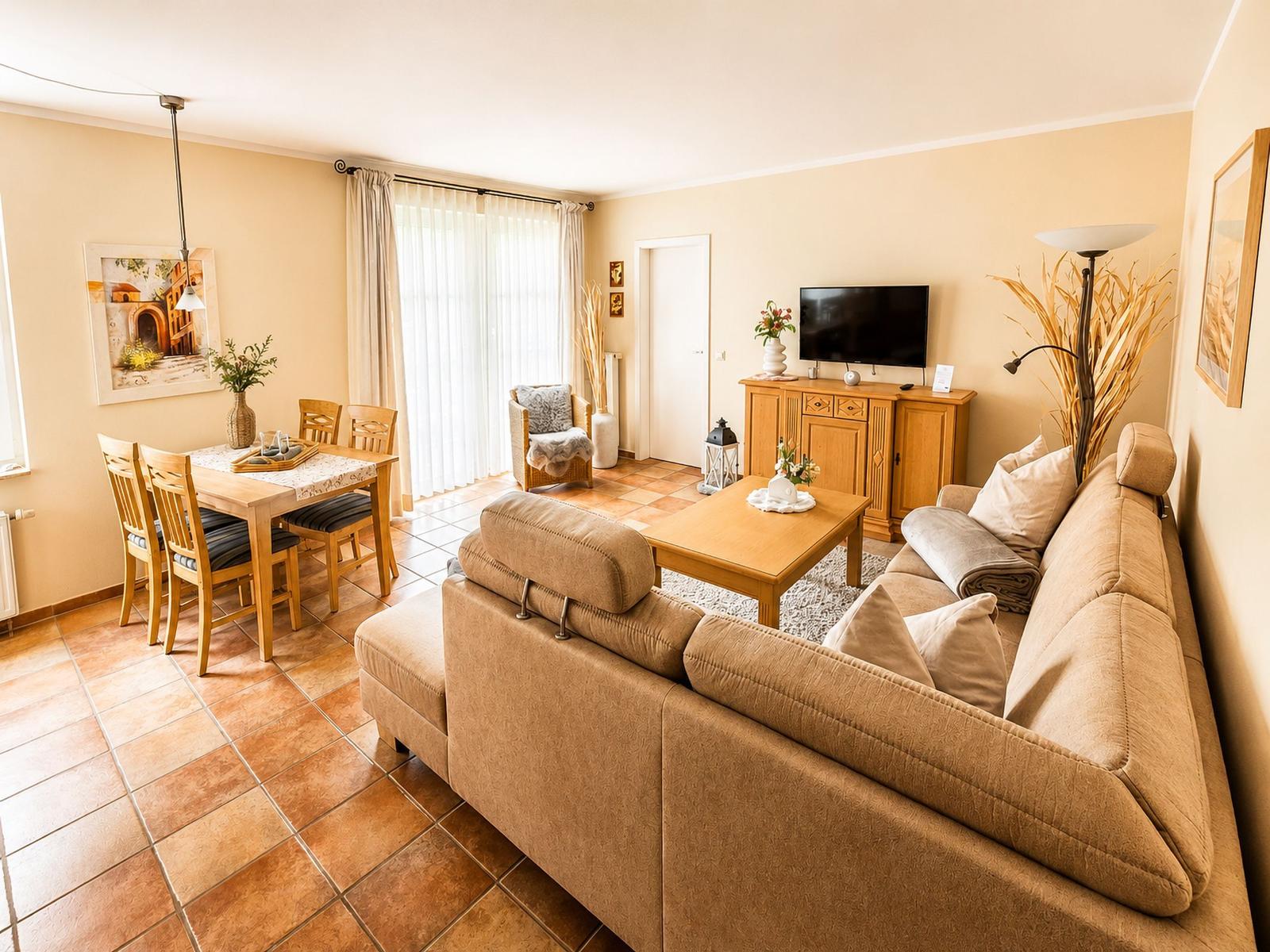 Wohn- und Essbereich mit Sofa, Esstisch und Fernseher.