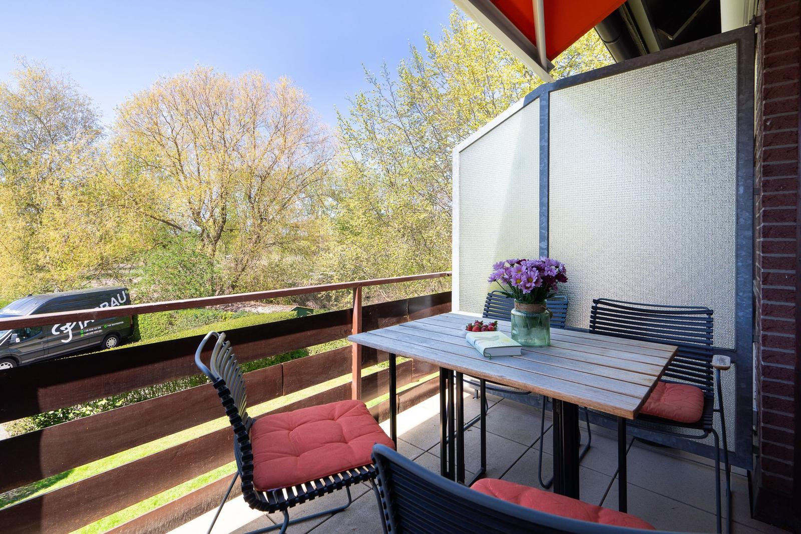Terrasse mit Tisch, Stühlen und Blick auf Bäume.