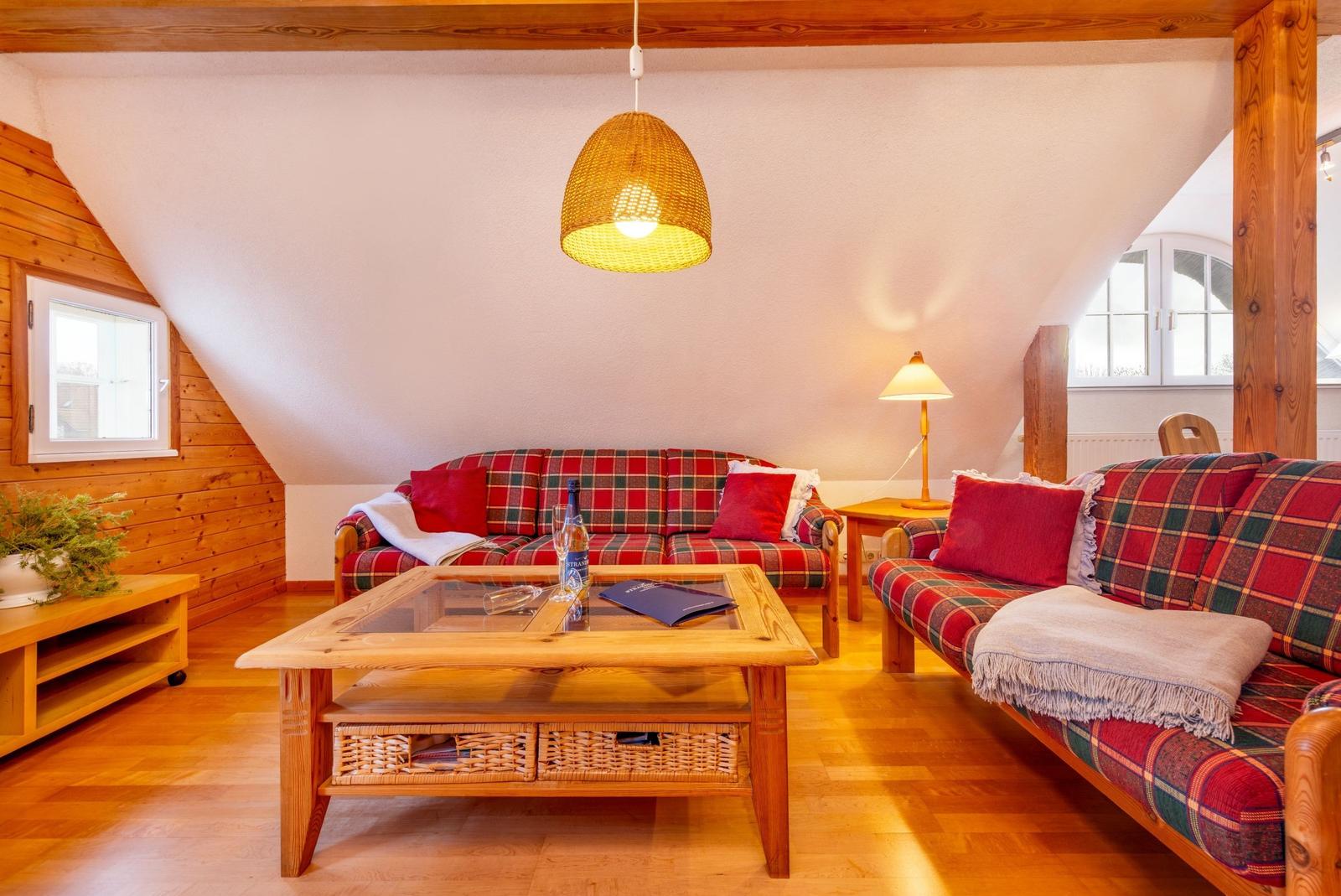 Wohnzimmer mit zwei Sofas, Holztisch und Deckenrahmen. Fenster und Lampe sichtbar.