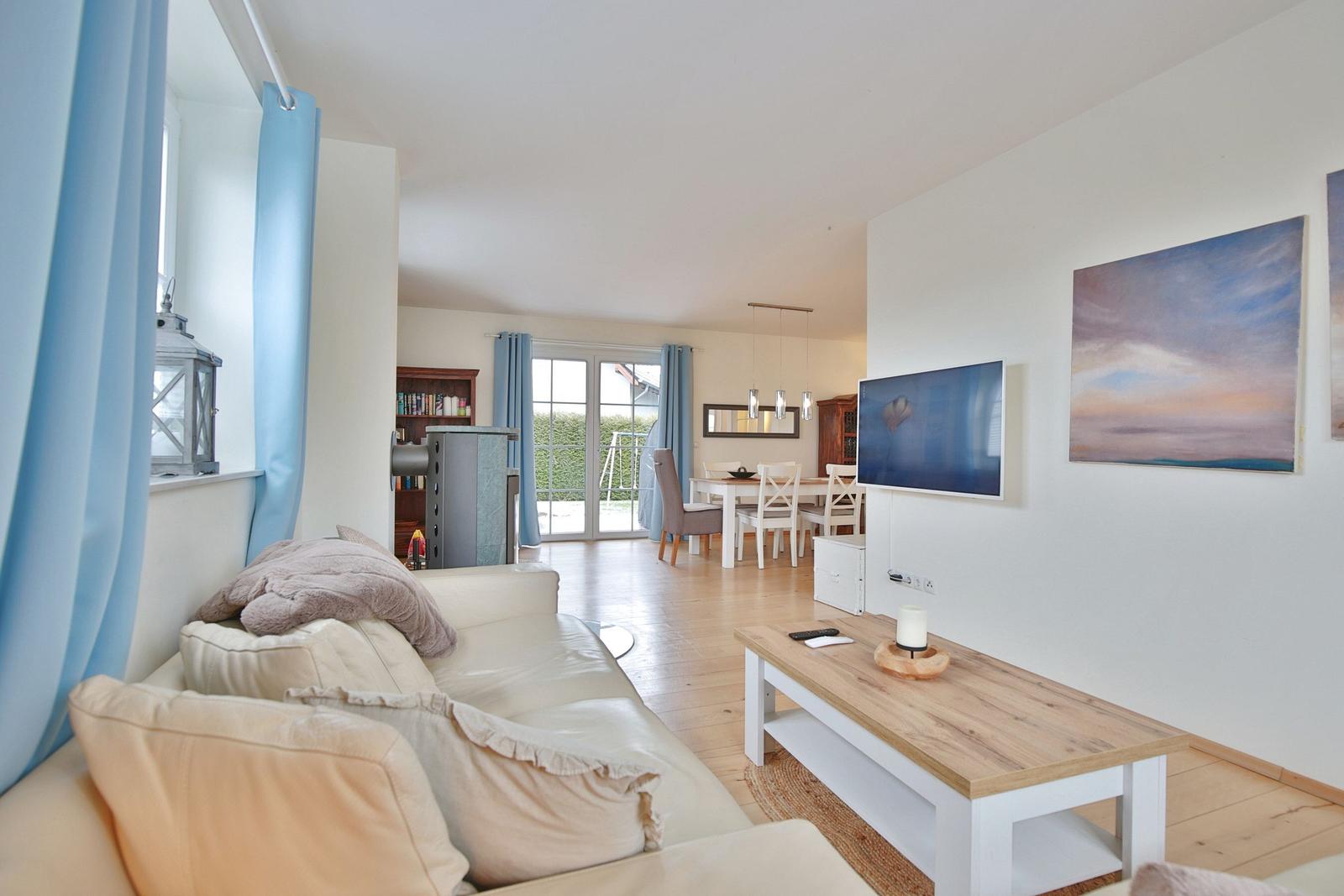 Wohnzimmer mit Sofa, Fernseher und Essbereich mit Tisch und Stühlen.