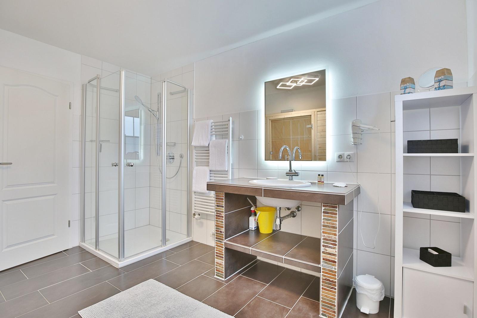 Badezimmer mit Dusche, Waschbecken und Spiegel