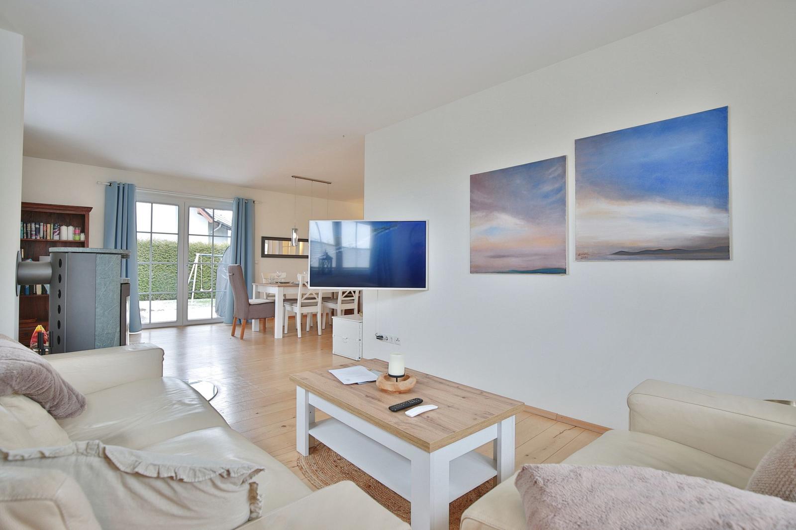 Wohnzimmer mit Sofa, Couchtisch und Fernseher. An der Wand hängen zwei Bilder.