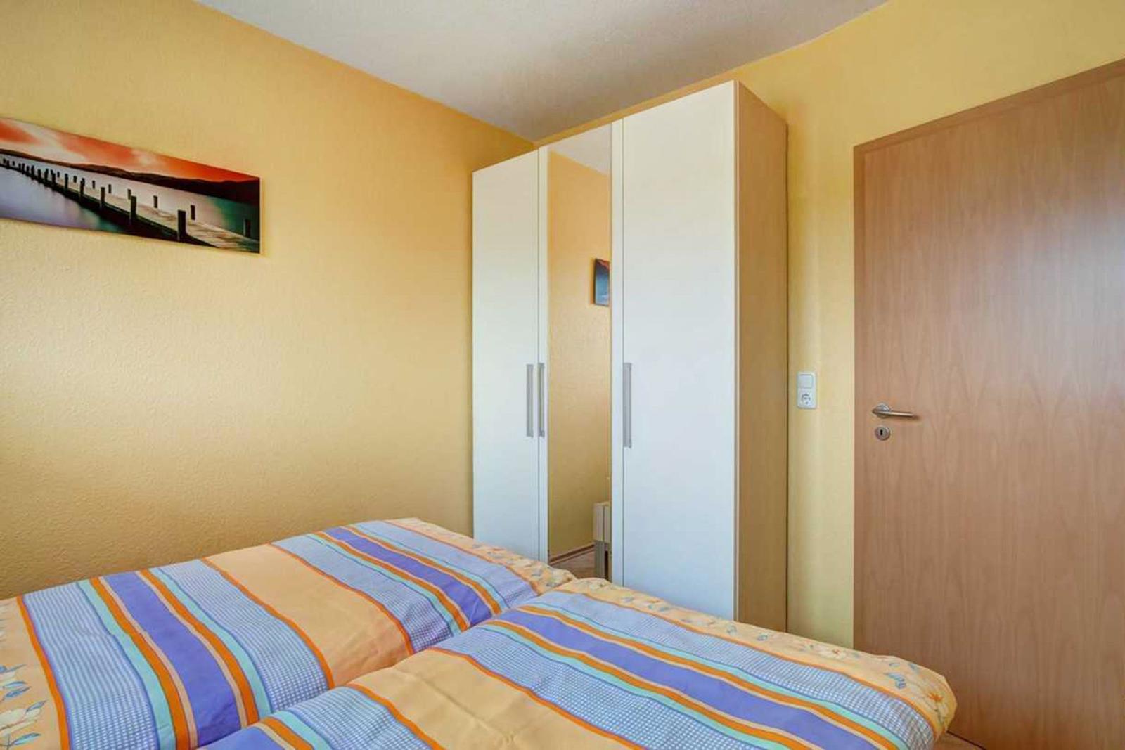 Zimmer mit zwei Betten, Kleiderschrank und Tür. Wandbild an der Wand.