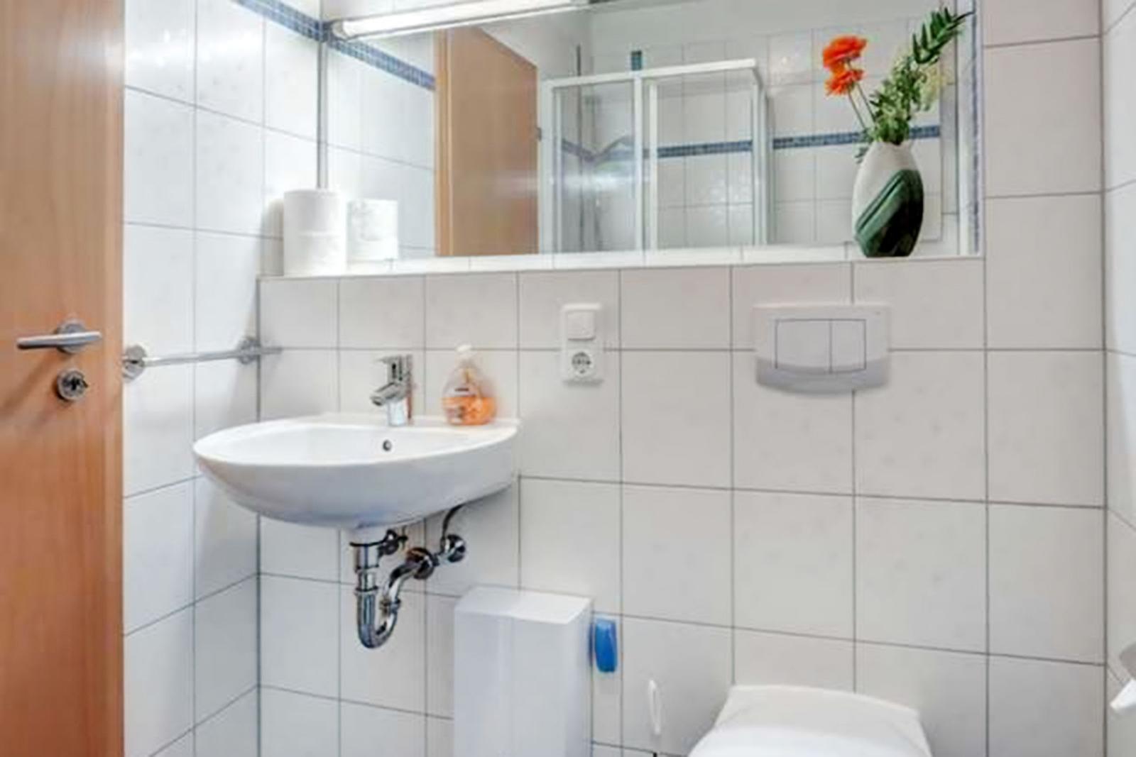 Badezimmer mit Waschbecken, Spiegel, Toilette und Dusche