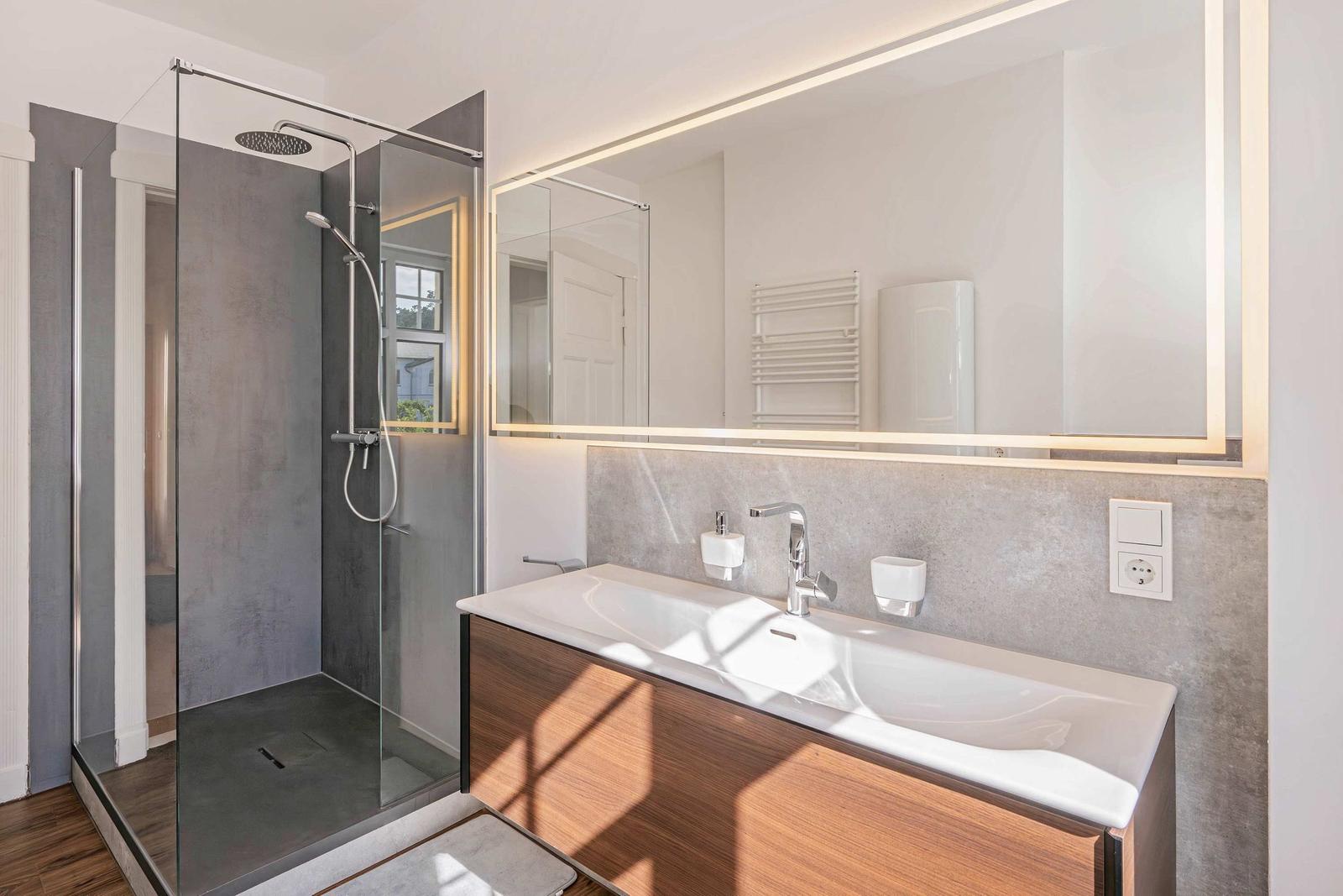 Bathroom with shower, sink, and lit mirror