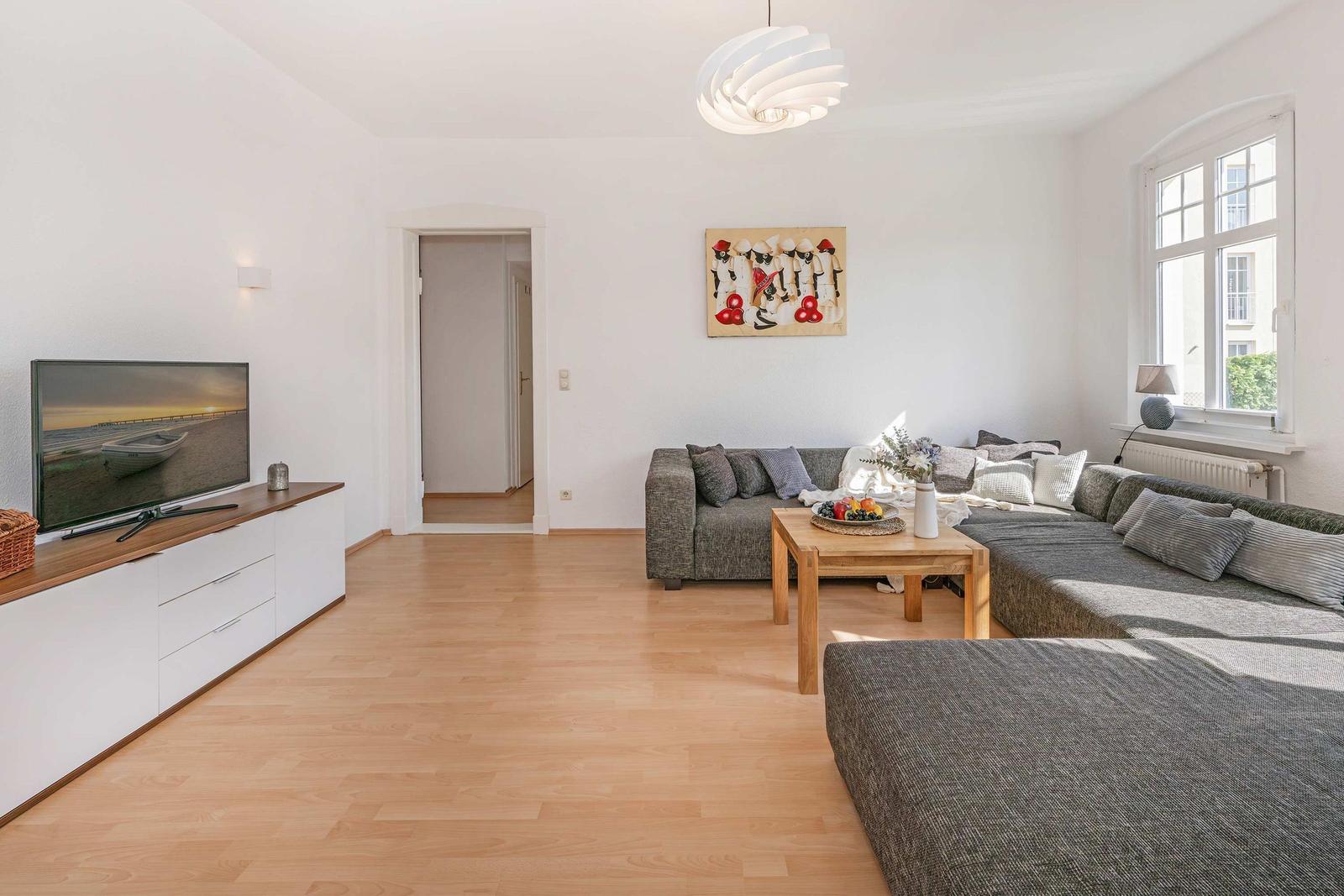 Living room with sofa, wooden table, and TV on wall.