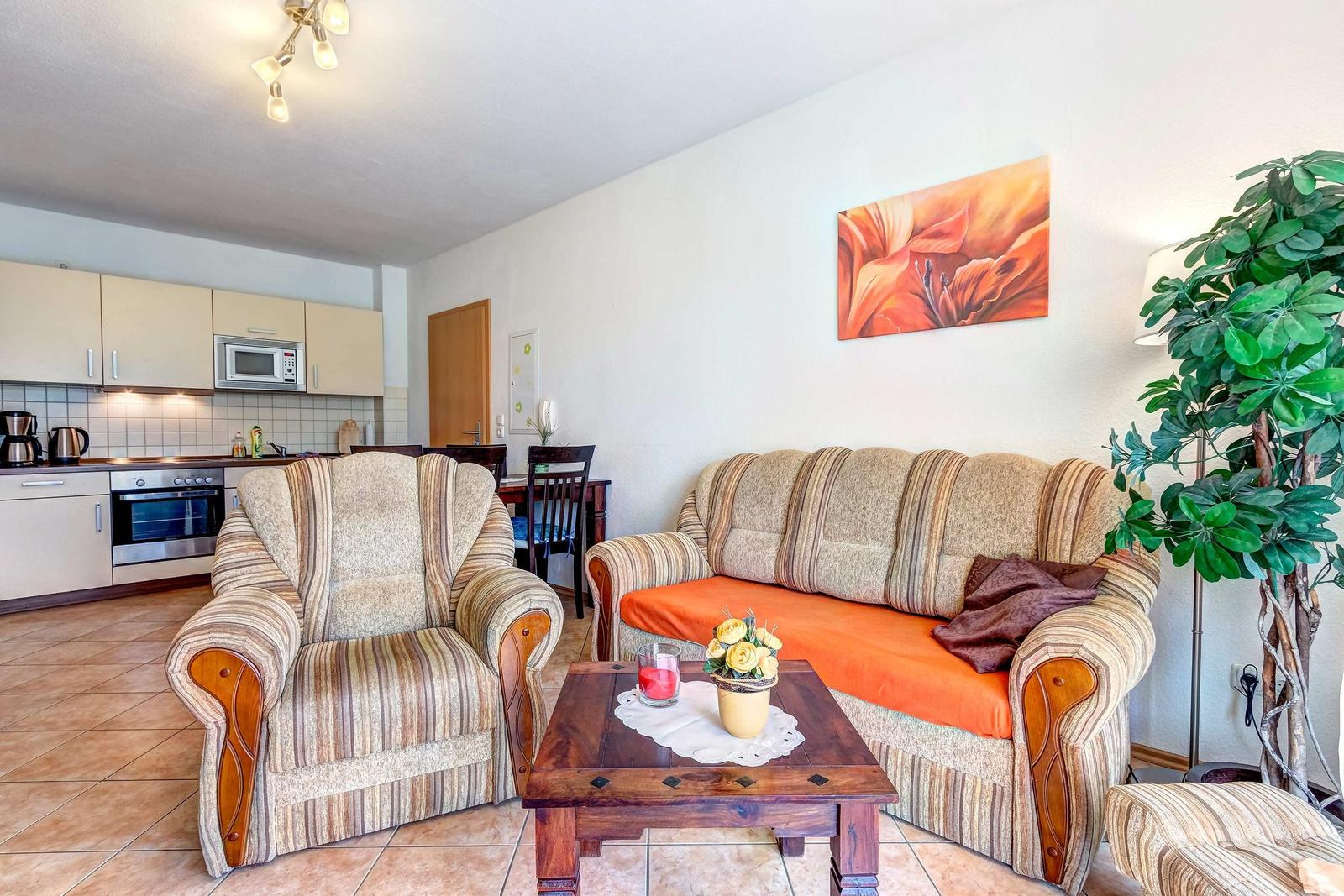 Wohn- und Küchenbereich mit Sofa, Sessel und Kücheneinrichtung.