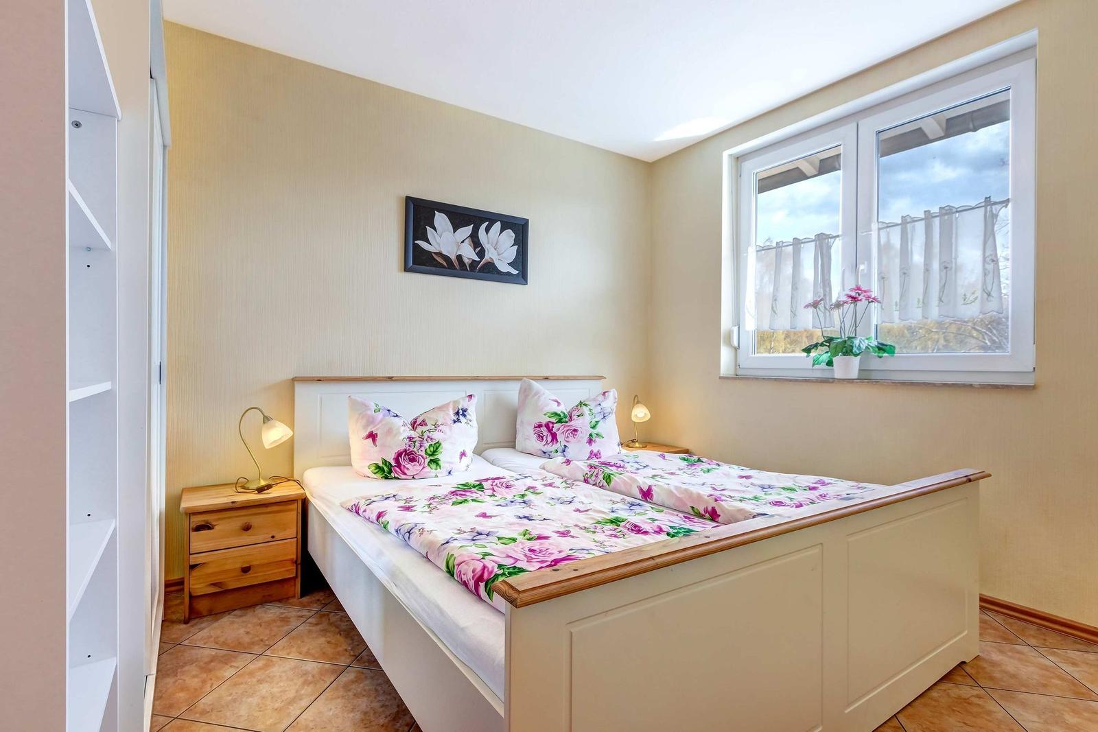 Schlafzimmer mit Doppelbett, Nachttischen und Fenster mit Blick.