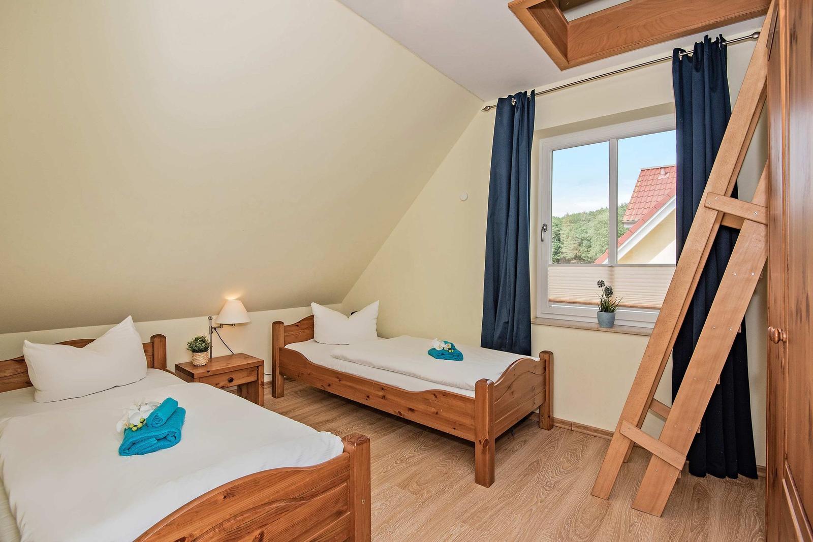 Zimmer mit zwei Betten, Holzboden und Fenster mit Blick auf Dach