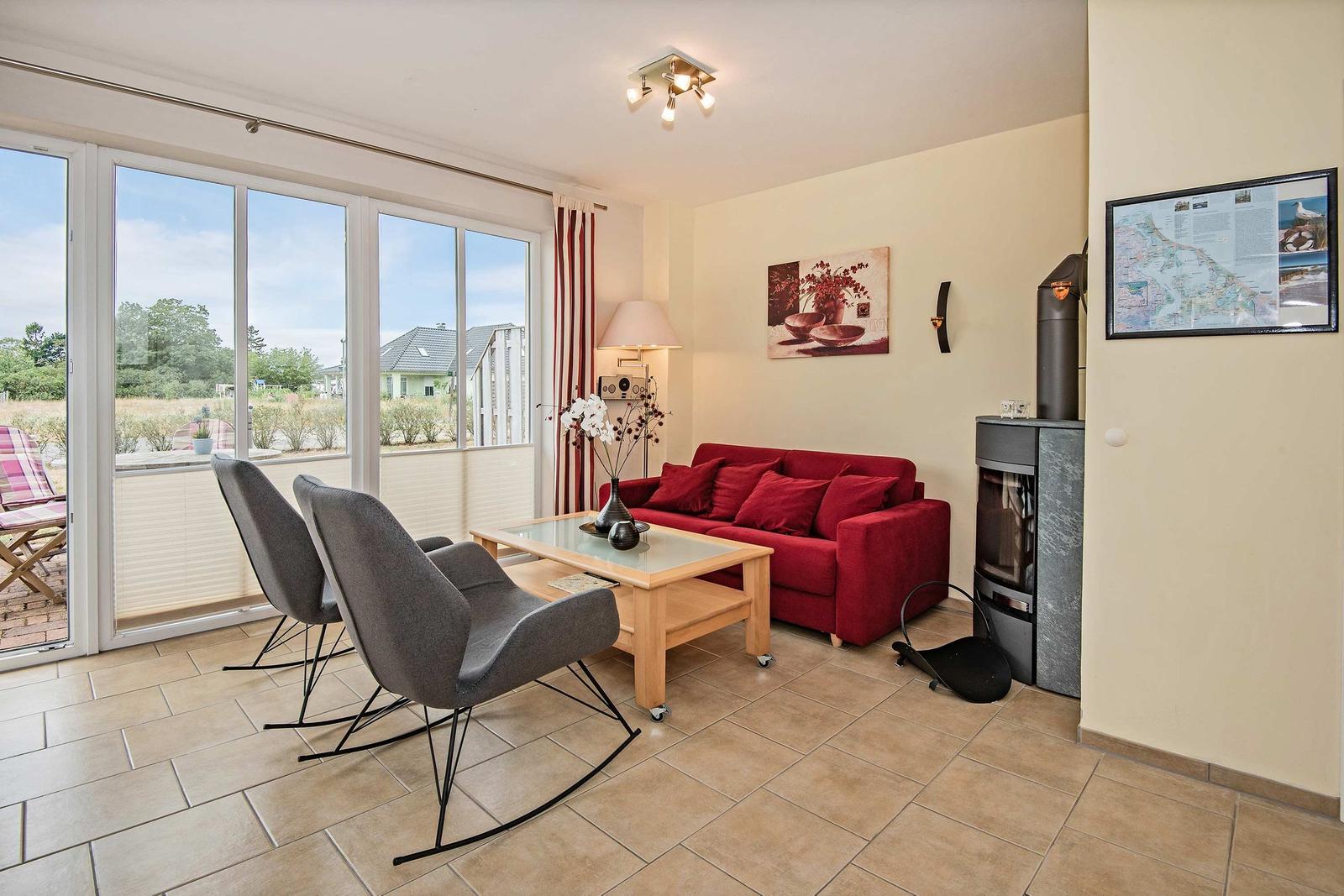 Wohnzimmer mit rotem Sofa, Glas-Tisch und Blick auf Terrasse.