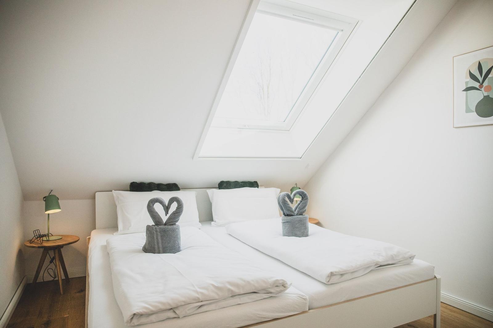 Schlafzimmer mit Dachschrägen, Dachfenster und Bett mit zwei Handtuchschwanen.