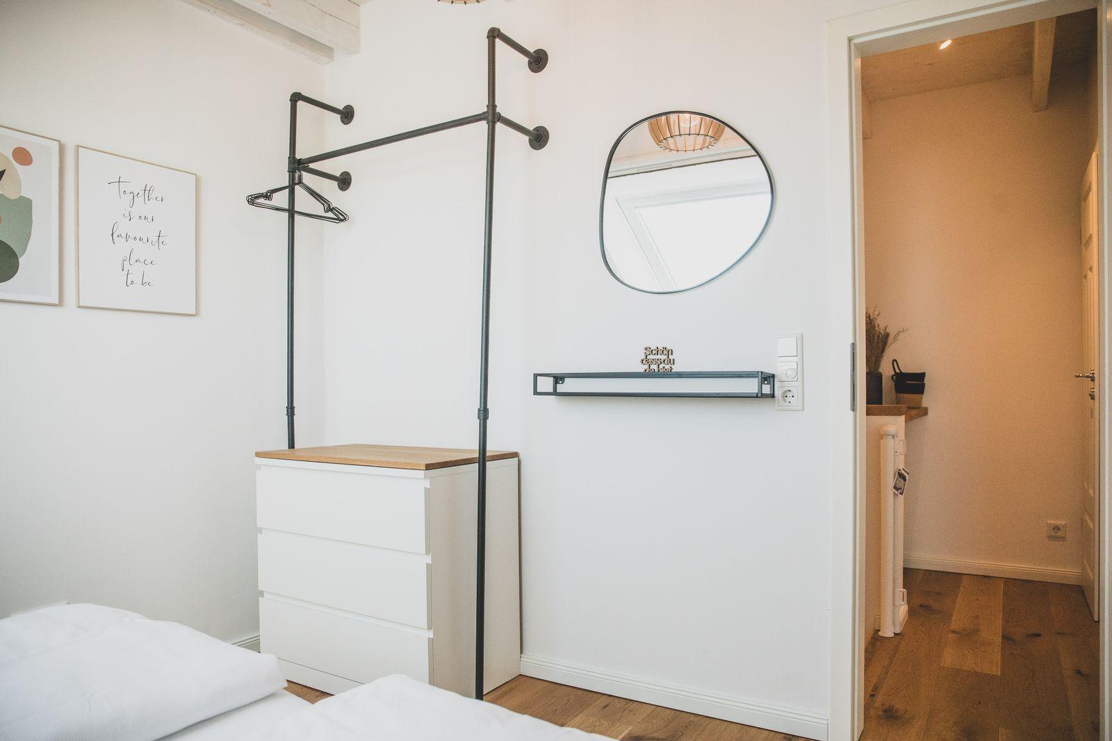 Schlafzimmer mit Kleiderständer, Spiegel und Schrank. Durchgang in angrenzenden Raum.