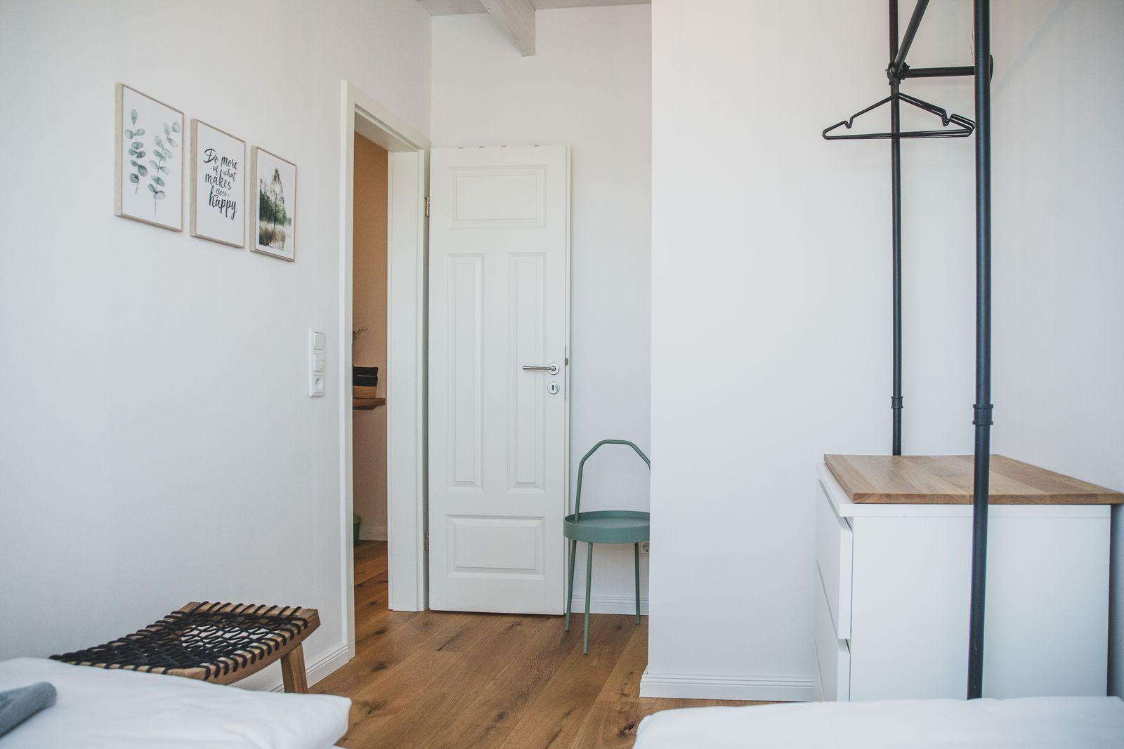 Schlafzimmer mit Holzboden, Bett, Kleiderschrank und Wandbildern.