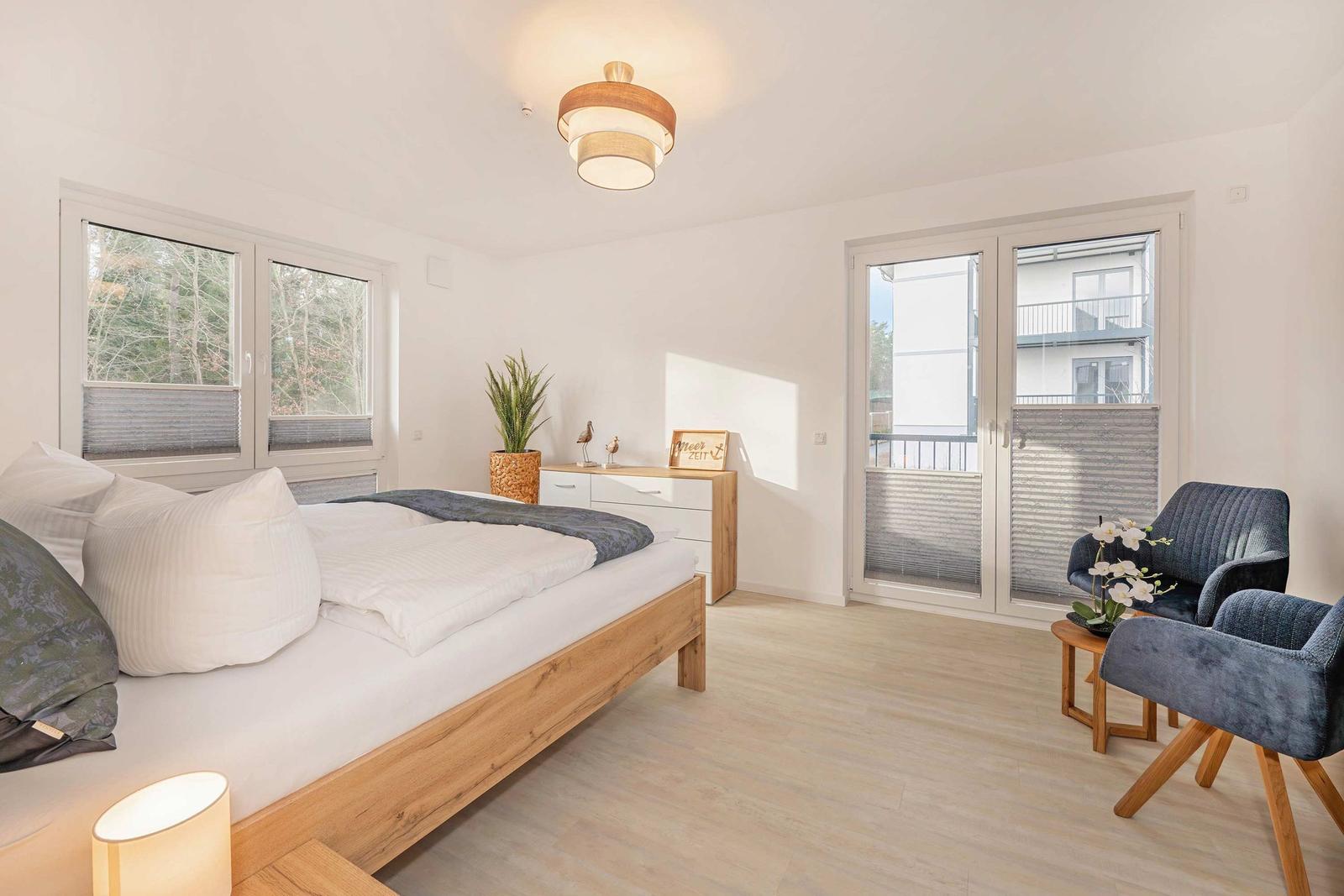 Schlafzimmer mit Bett, Schrank, Sessel und Balkontür.