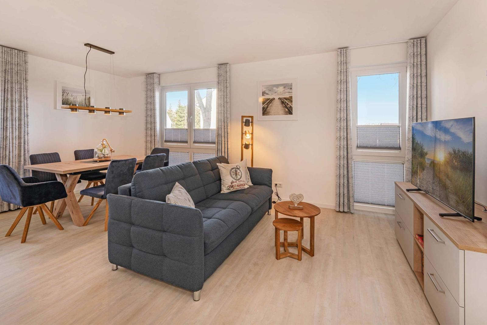 Wohn- und Essbereich mit Sofa, Tisch, Stühlen und Fernseher.