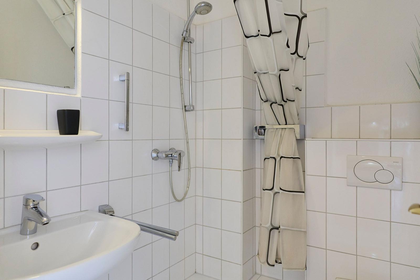 Badezimmer mit Dusche, Waschbecken und Spiegel