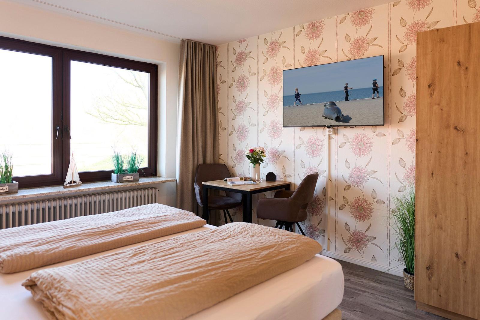 Zimmer mit Doppelbett, Schreibtisch, Fernseher und Fenster mit Blick.