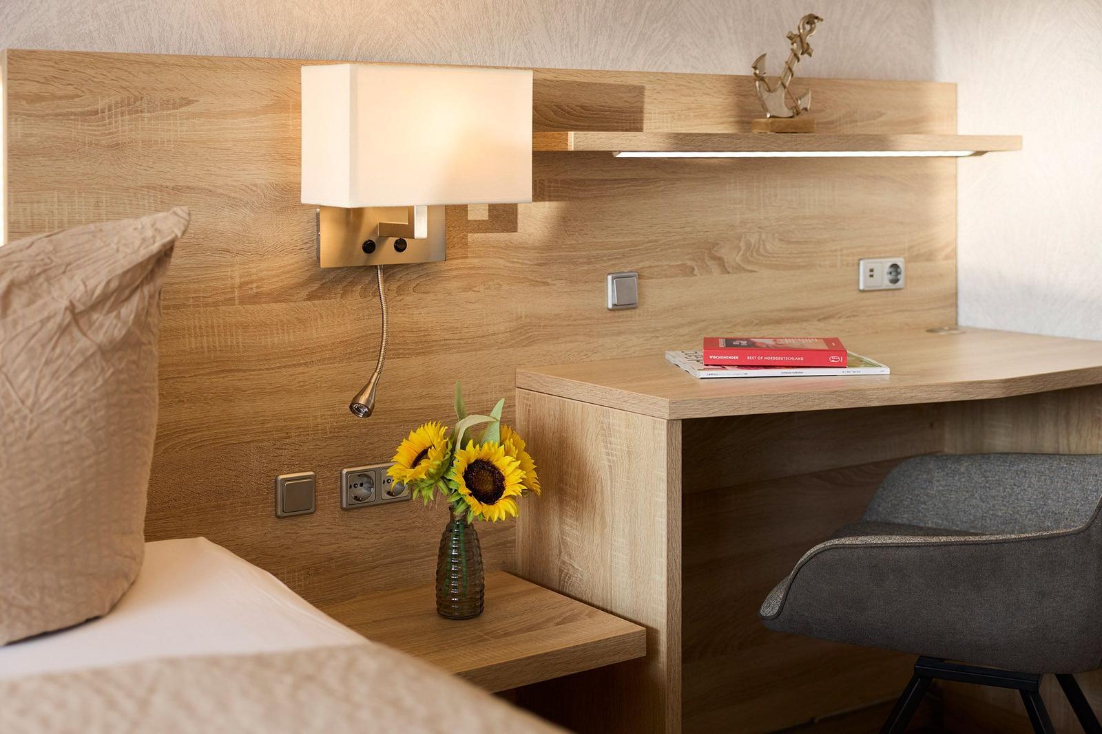 Schreibtisch mit Stuhl, Lampe und Sonnenblumen neben dem Bett.