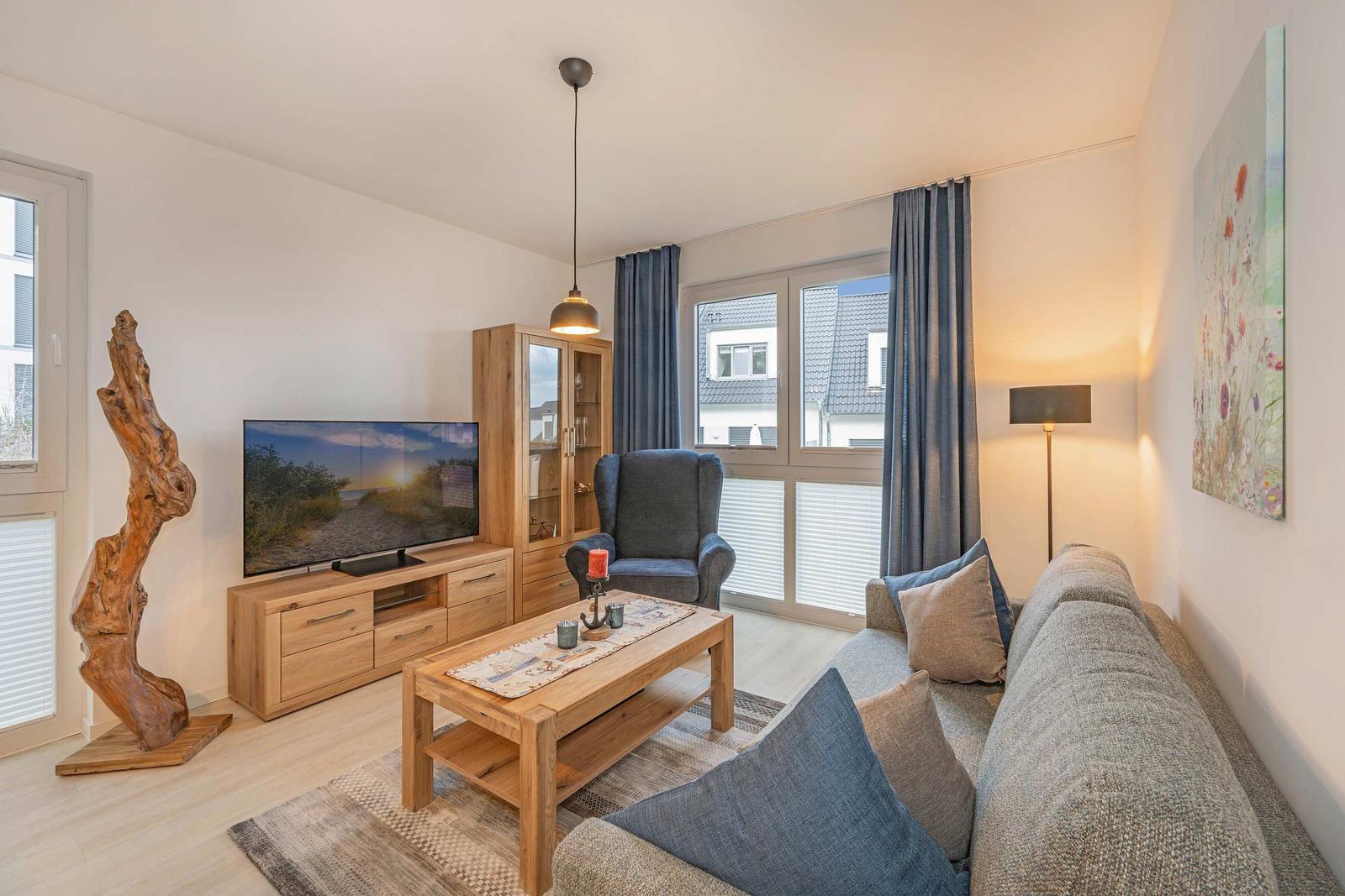 Wohnzimmer mit Sofa, Couchtisch, Fernseher und Sessel.