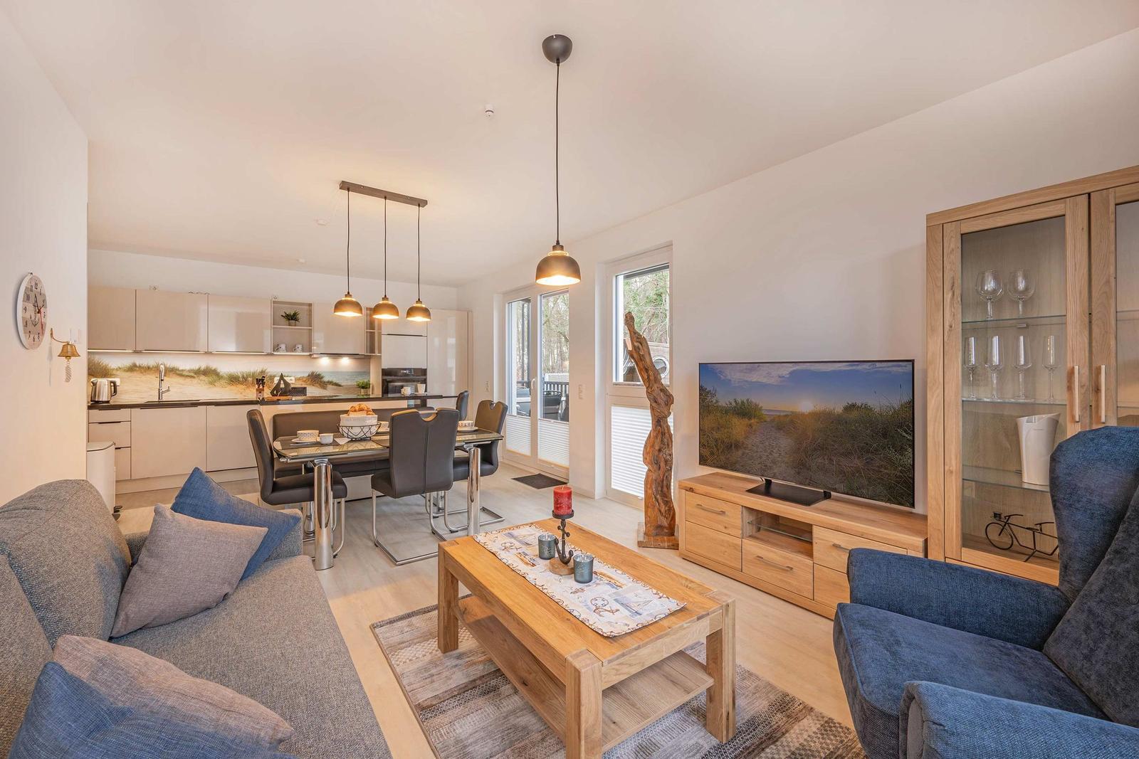 Wohn- und Essbereich mit Küchenzeile, Sofa, Sessel und Fernseher.