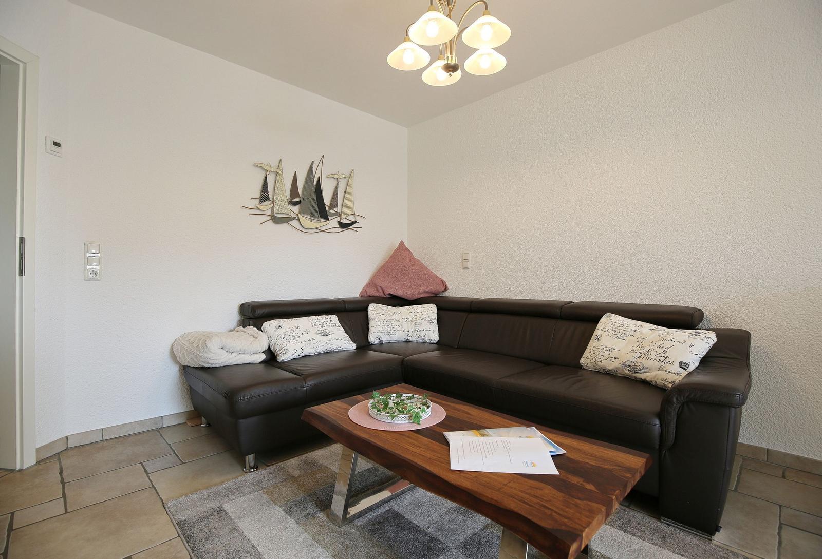 Living room with corner sofa, wooden table, and wall decoration with sailboats.