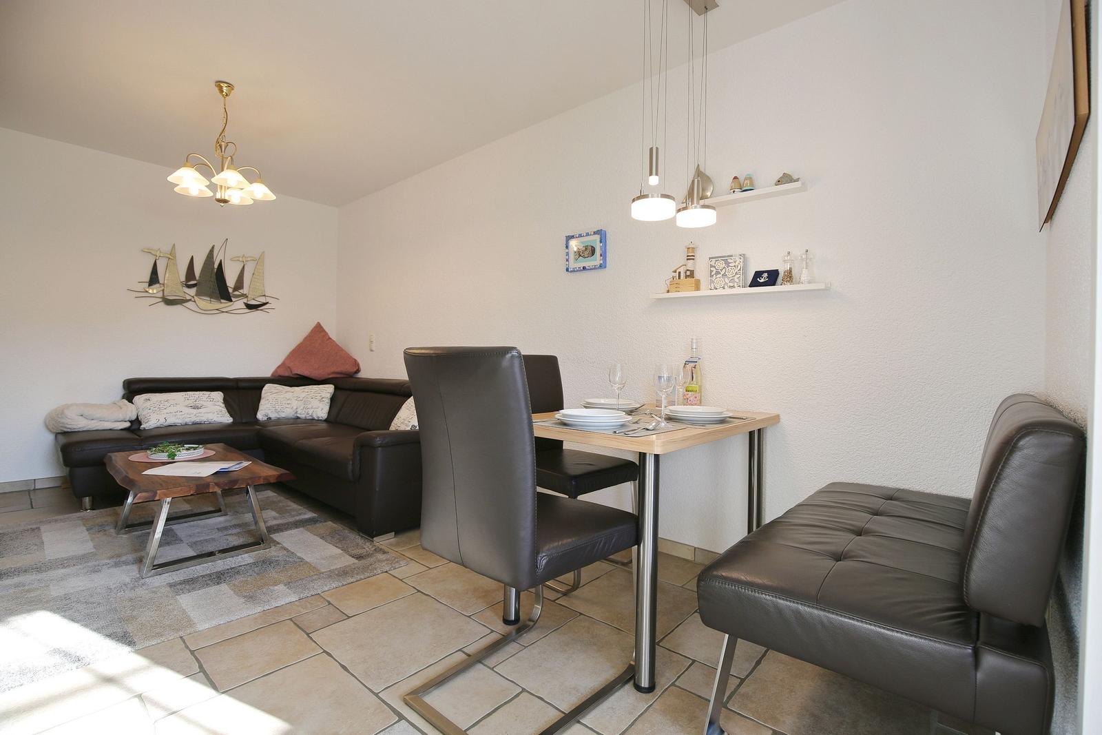 Living and dining area with sofa, table, and chairs. Wall decor and lighting visible.