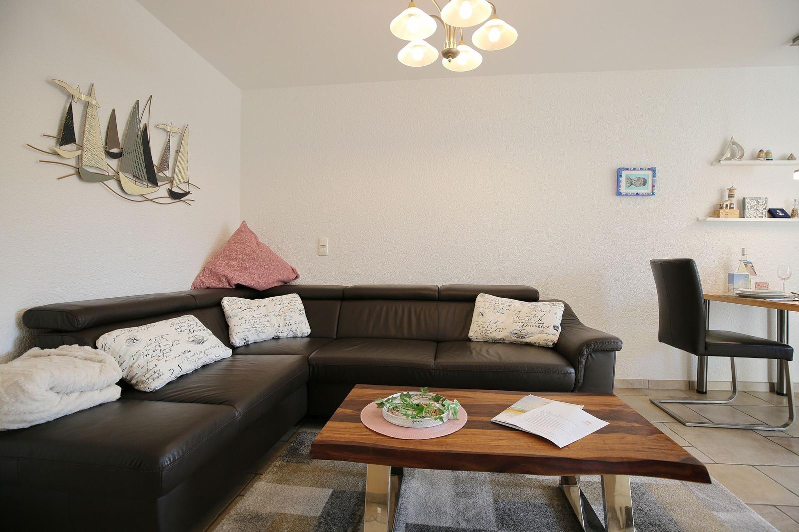 Living room with L-shaped sofa, wooden table, and wall decor with sailboats.