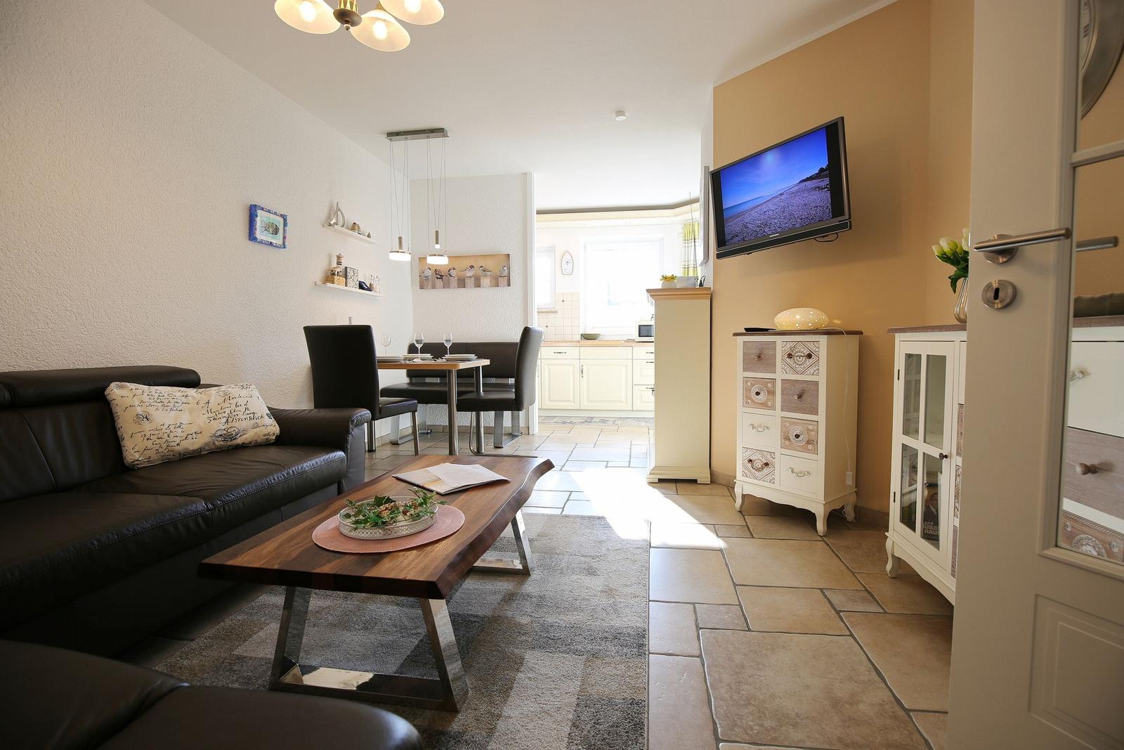 Living and dining area with sofa, table, and TV mounted on the wall.