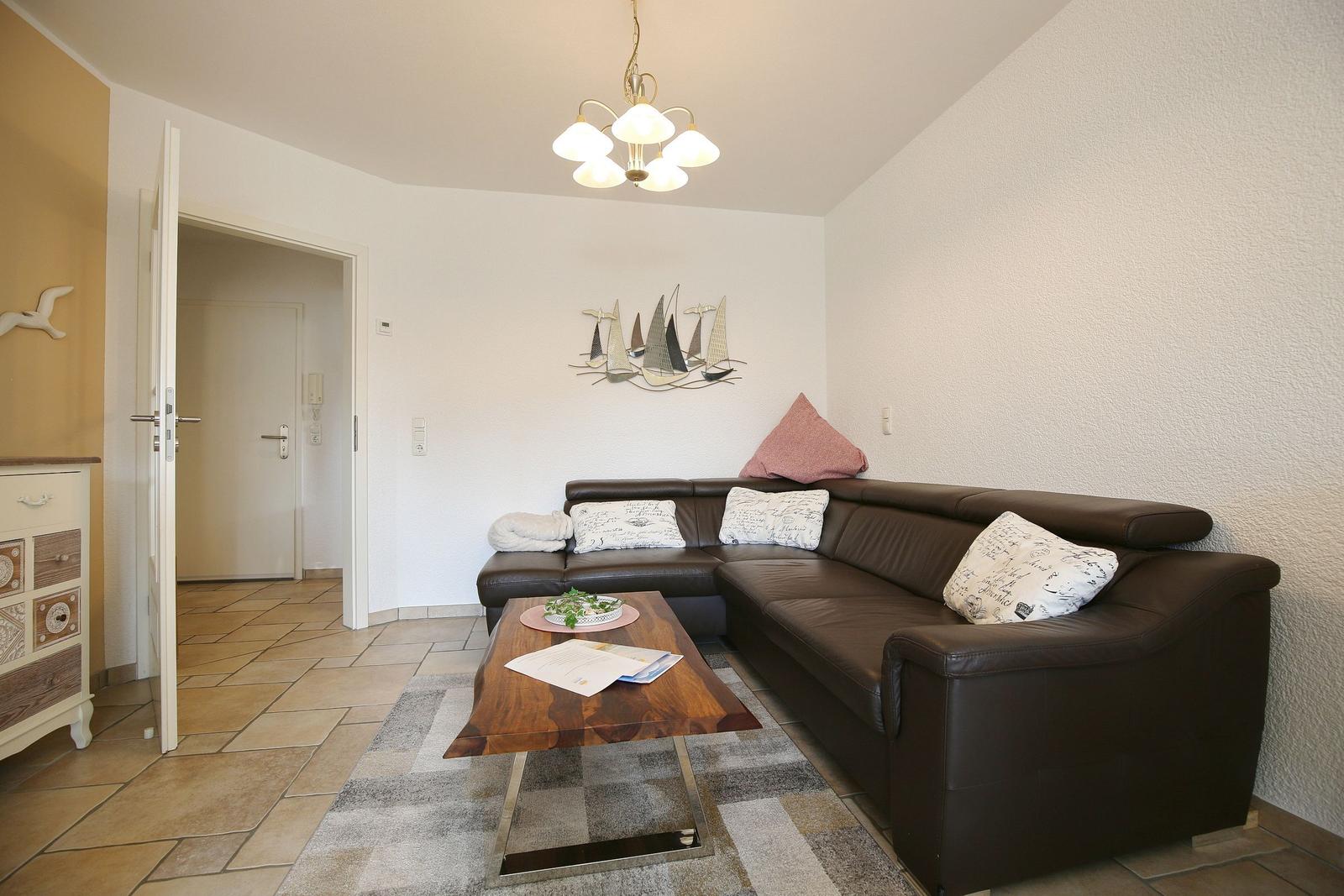 Living room with brown sofa, wooden table, and wall decoration with sailboats.