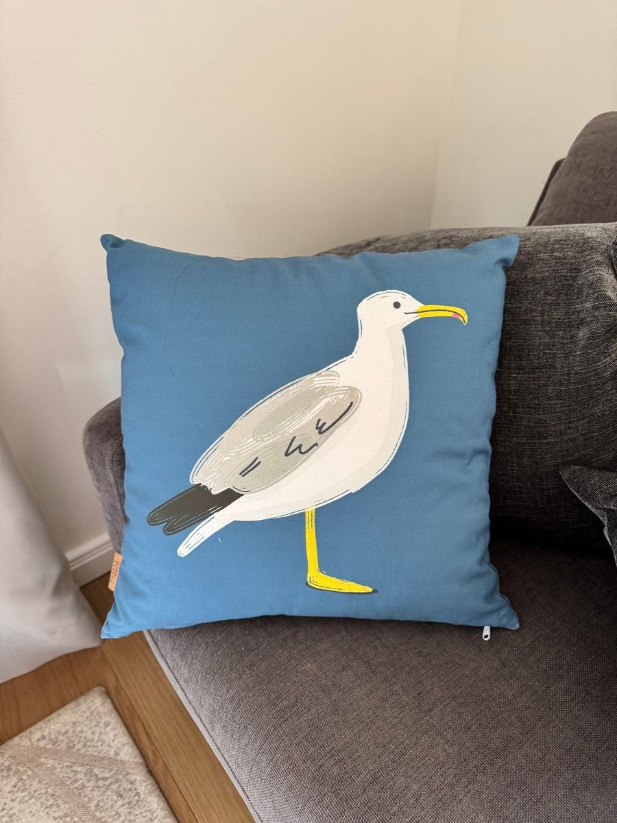 Kissen mit Seemöwe-Motiv auf grauem Sofa