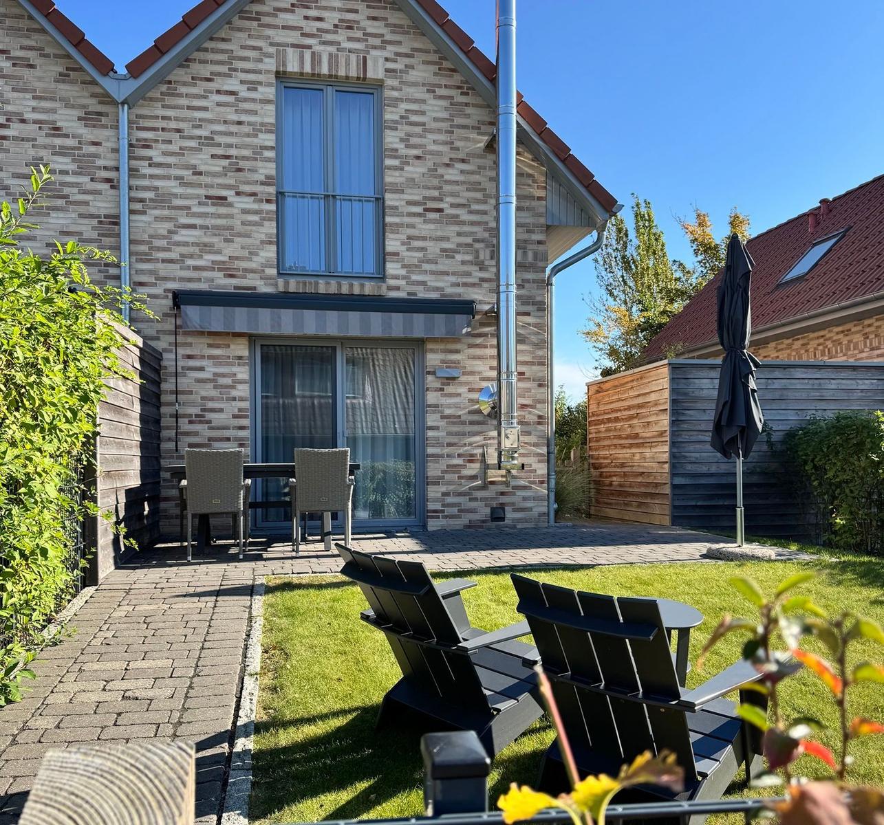 Haus mit Garten, Terrasse und Sitzgelegenheiten unter freiem Himmel.