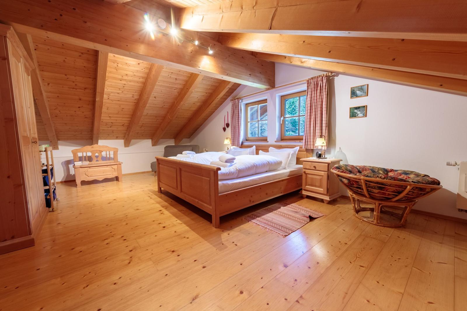 Schlafzimmer mit Holzboden, Dachschrägen und großem Bett.