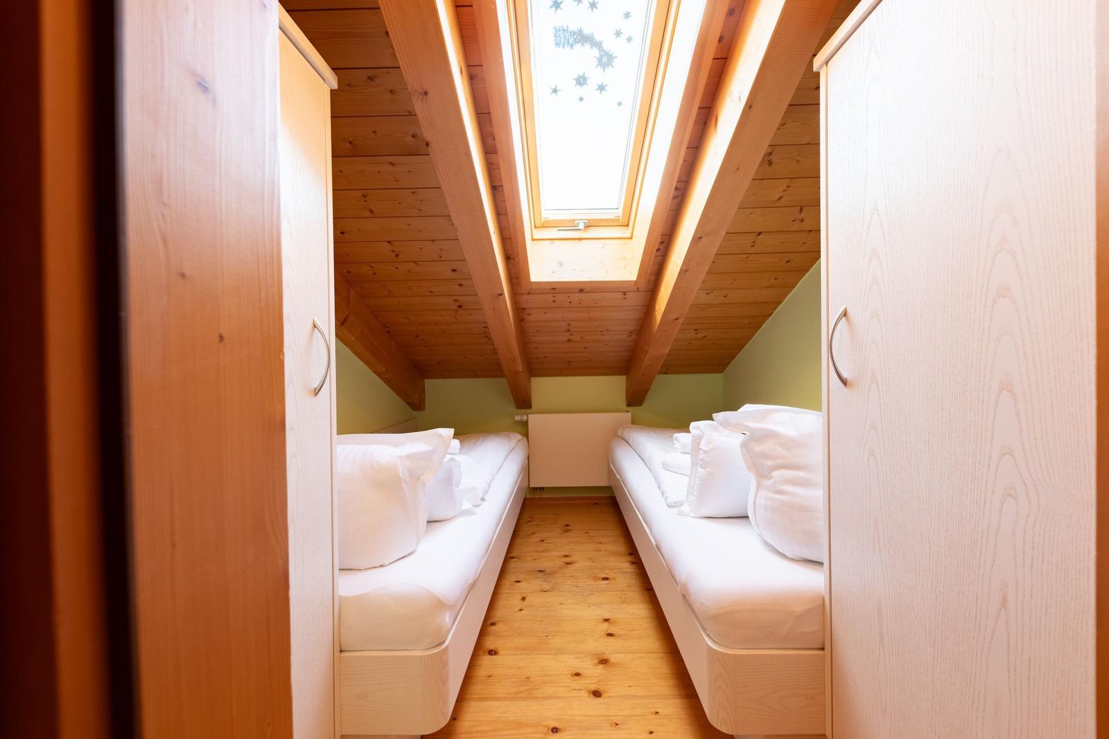 Zwei Betten unter Dachschrägen mit Holzboden und Dachfenster.
