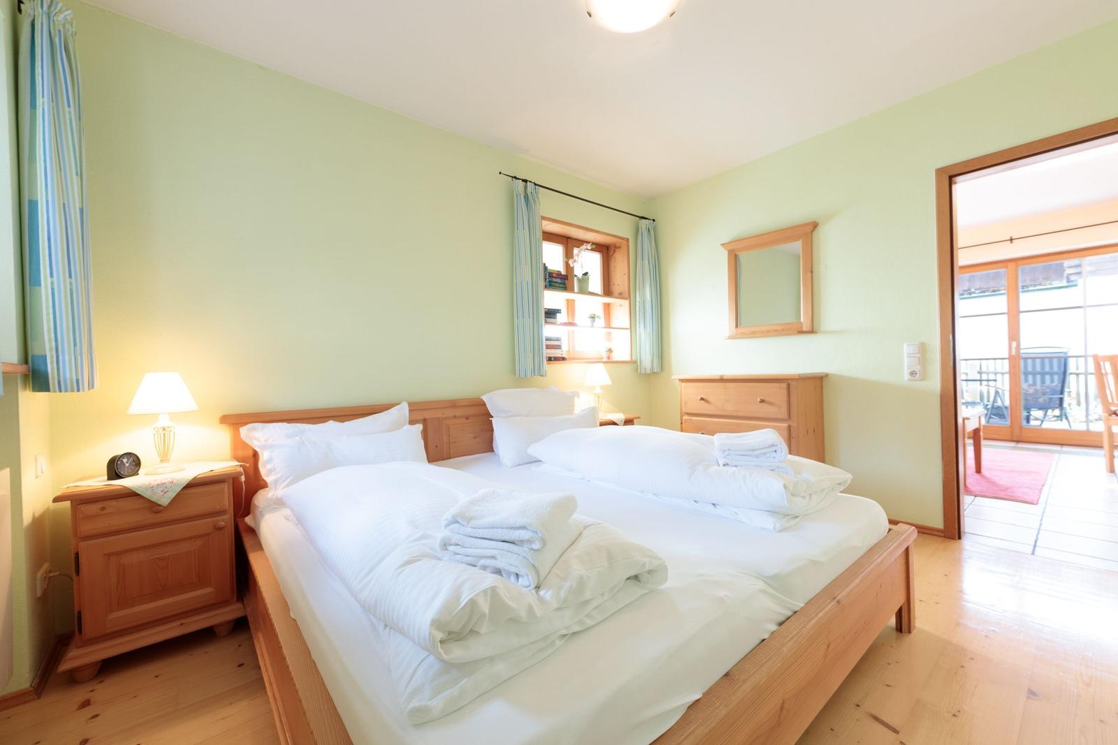 Ein Schlafzimmer mit einem Bett, Nachttischen und einem Schrank. Durchgang zur Terrasse.