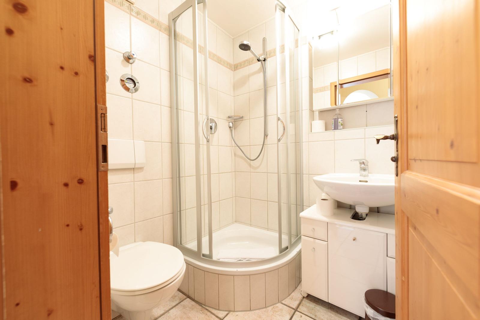 Badezimmer mit Dusche, Waschbecken und Toilette.