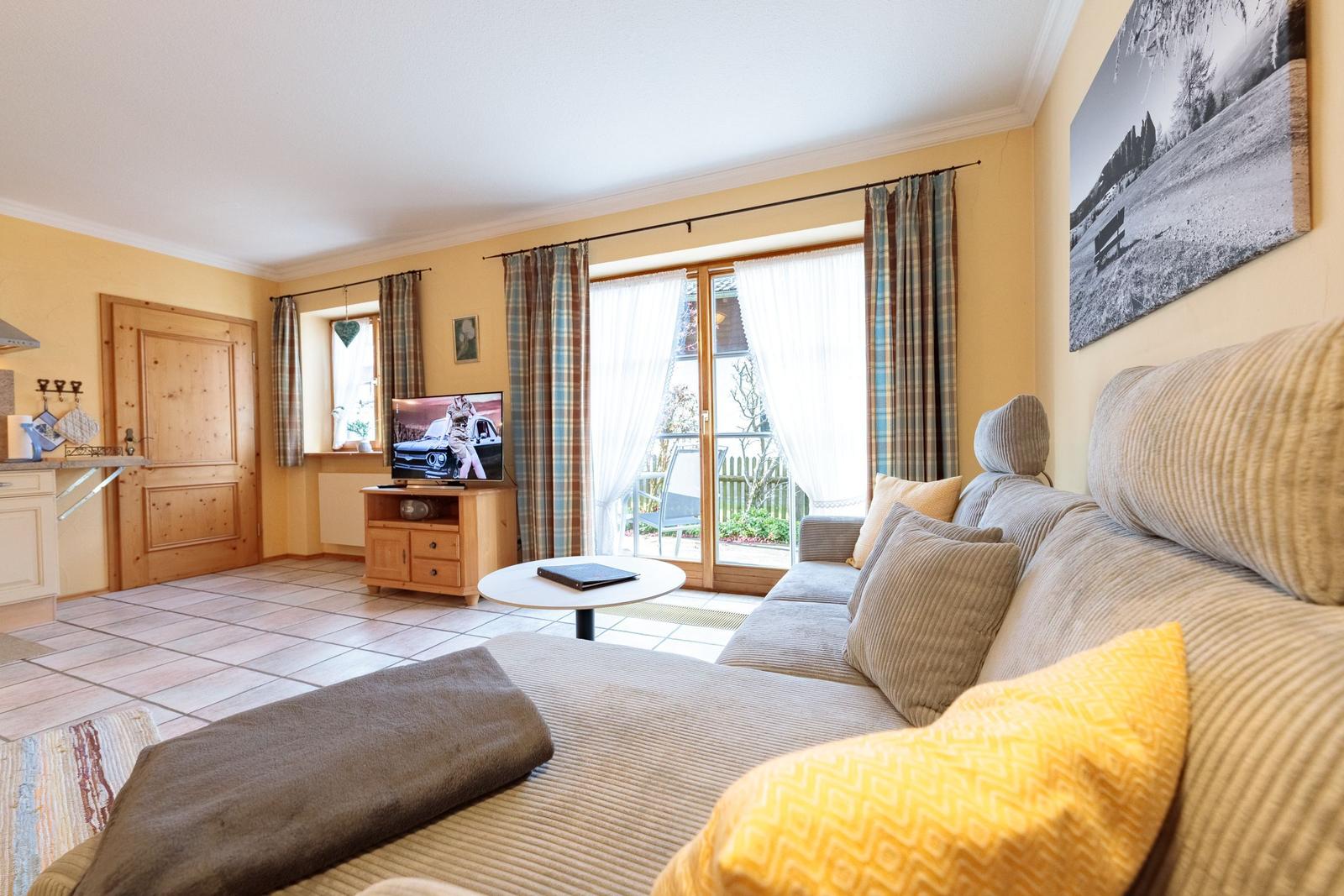 Wohnzimmer mit Sofa, Fernseher und Balkontür.