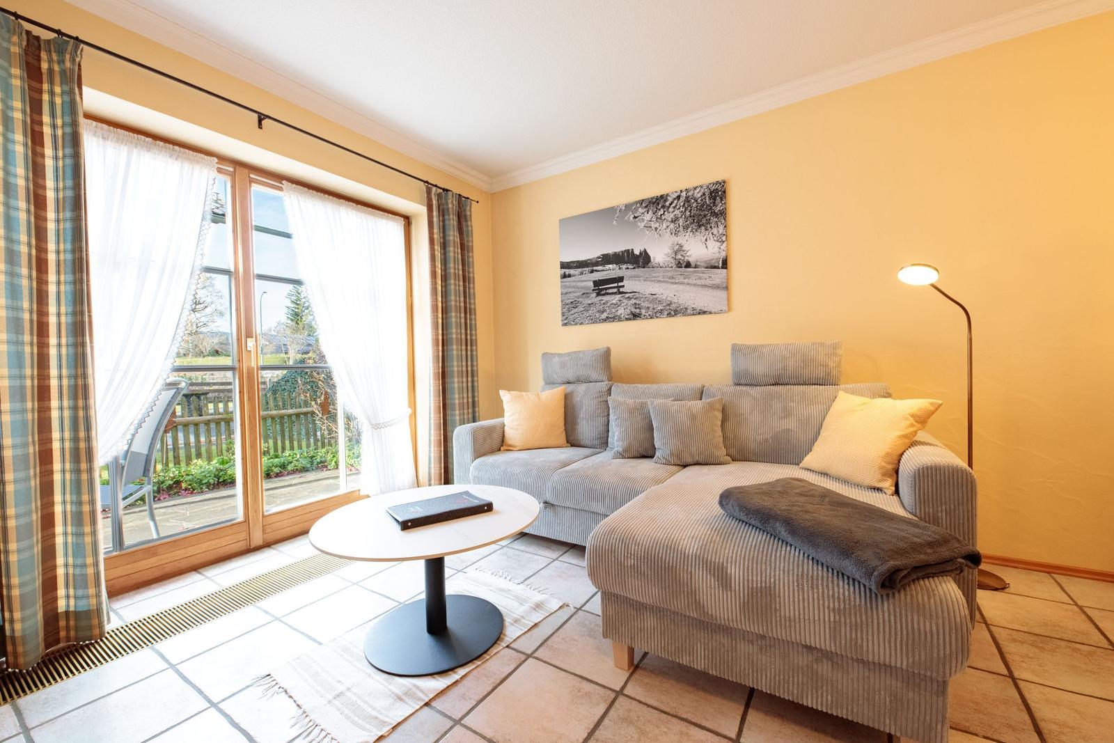 Wohnzimmer mit Sofa, Tisch und Balkon. Wandbild und Stehlampe.