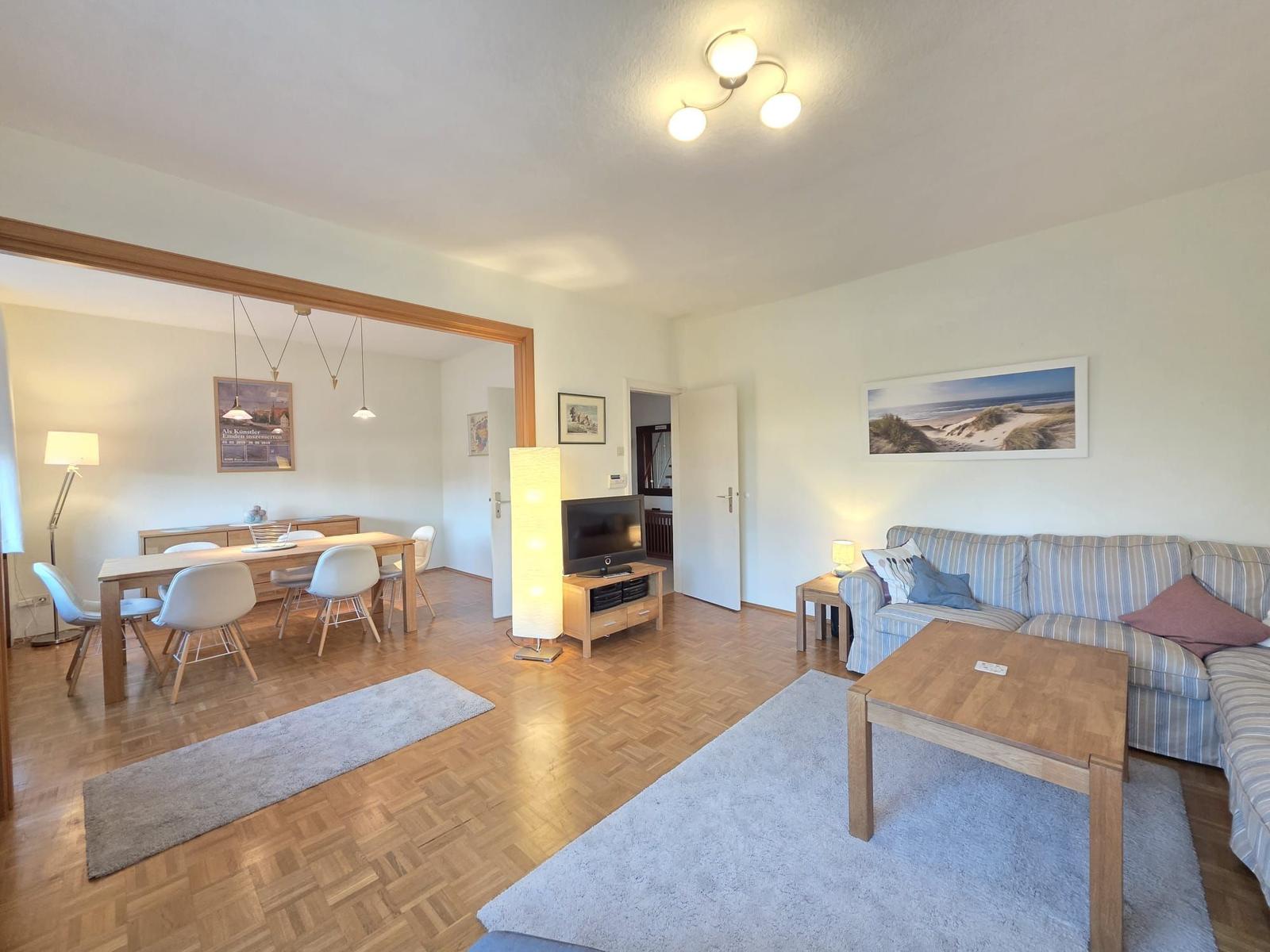 Wohn- und Essbereich mit Sofa, Esstisch und Fernseher.