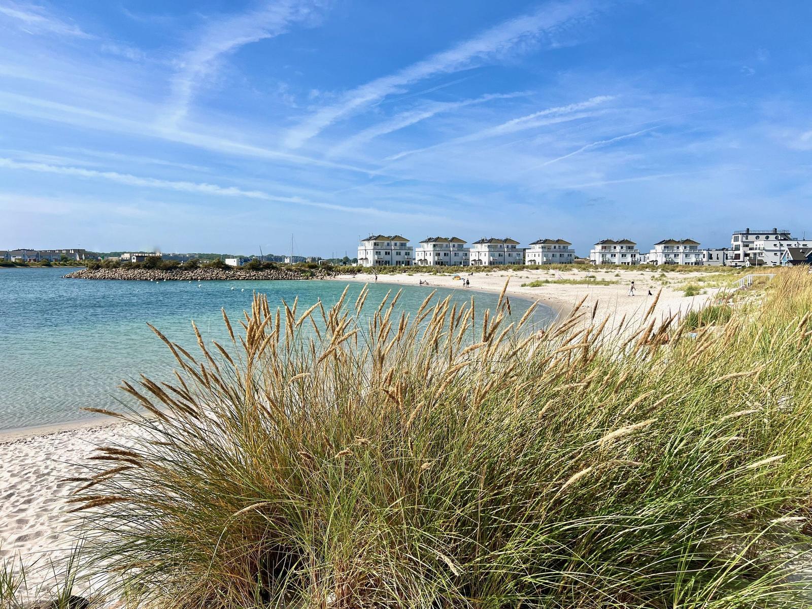 Strand mit Dünenvegetation und Ferienhäusern am Ufer