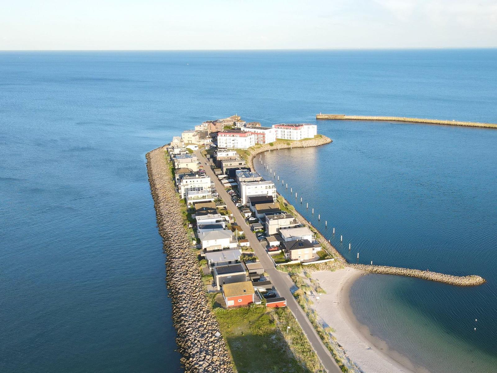 Aerielansicht einer Küstenstadt mit Häusern, Straße und Strand.