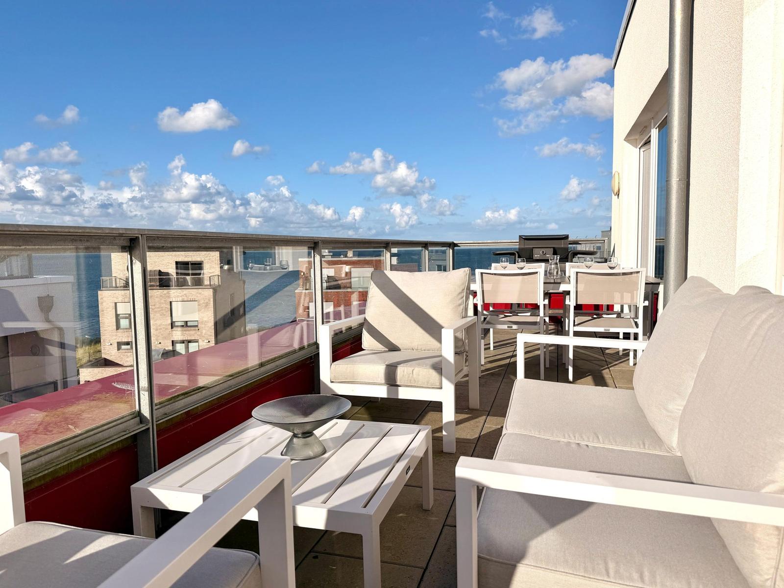 Terrasse mit Sitzgelegenheiten und Blick auf den Himmel und Gebäude.