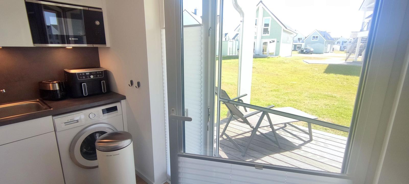 Kitchen with washing machine and view of terrace with lounge chair