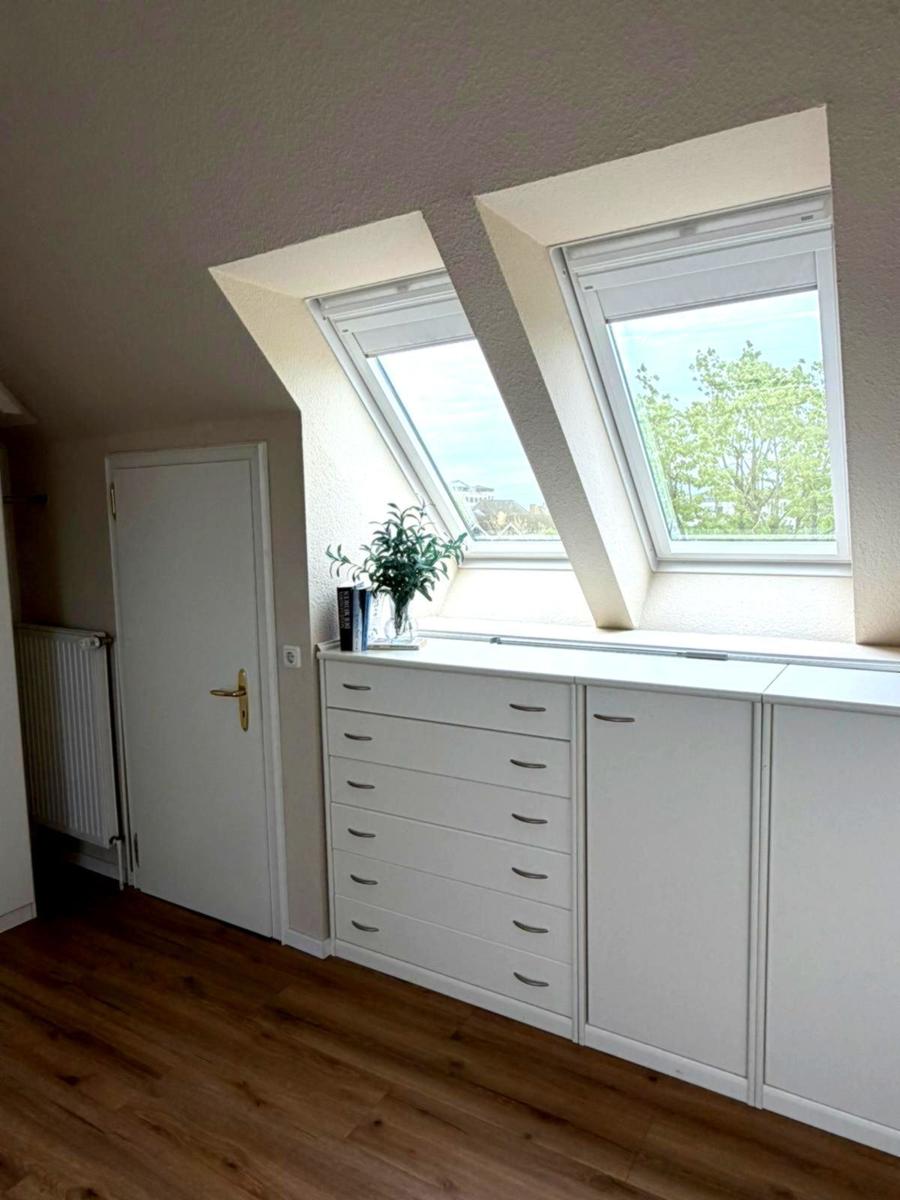 Schlafzimmer mit Dachfenstern, weißem Schrank und Holzboden.