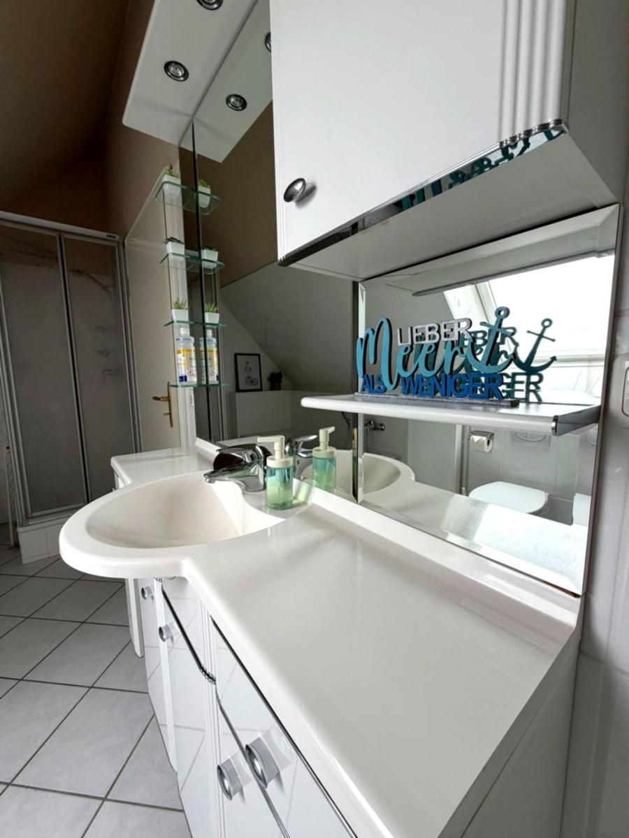 Badezimmer mit Waschbecken, Spiegel und Dusche. Dekorative Aufschrift an Spiegel.