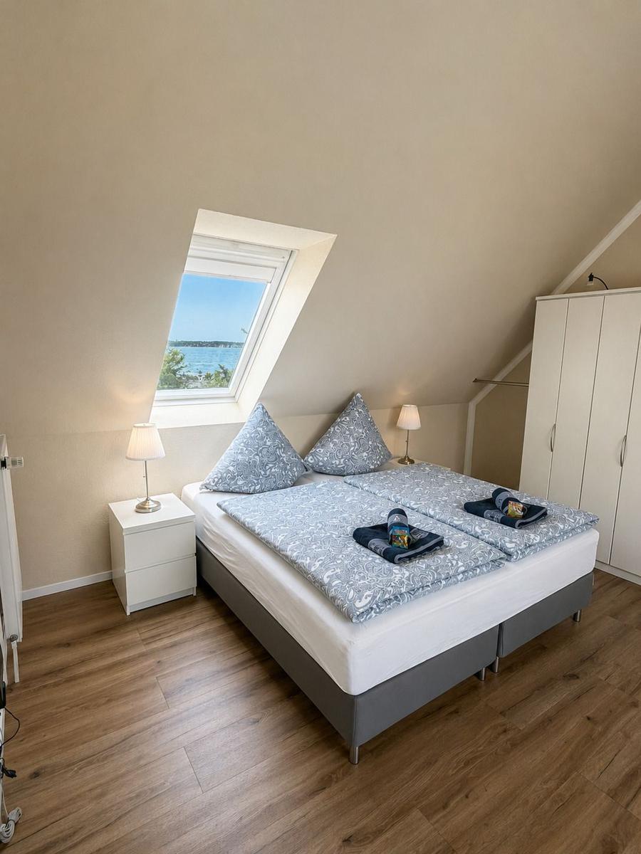 Schlafzimmer mit Doppelbett, Dachfenster und Kleiderschrank.