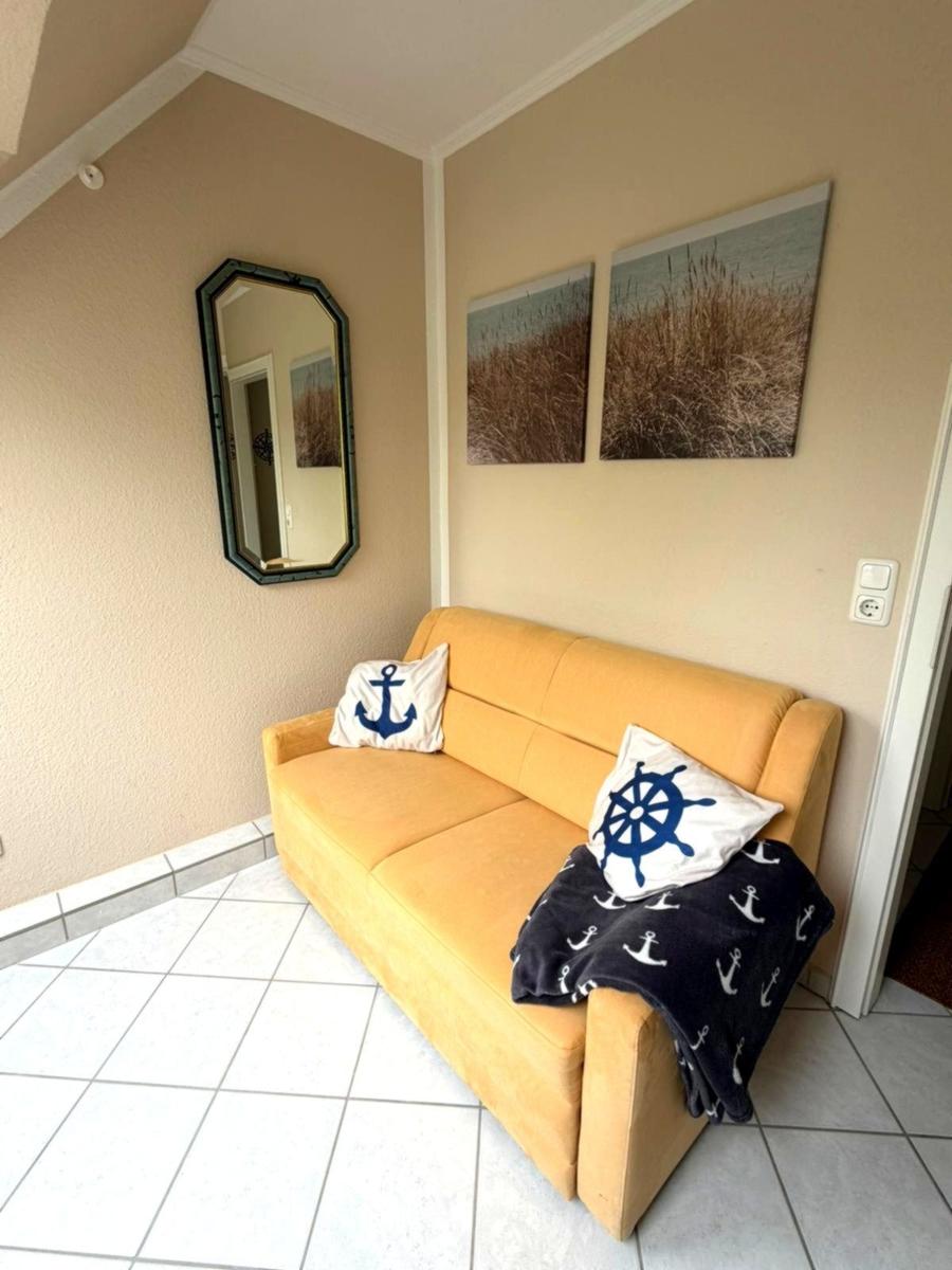 Gelber Sofa mit Kissen und Decke, Wandbilder und Spiegel im Raum.
