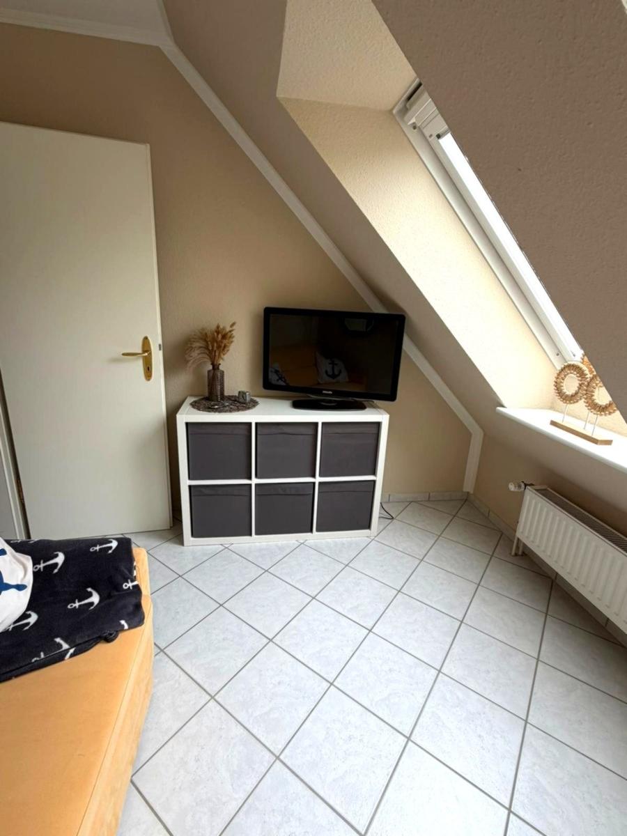 Schlafzimmer mit Dachschräge, TV, Schrank und Fenster