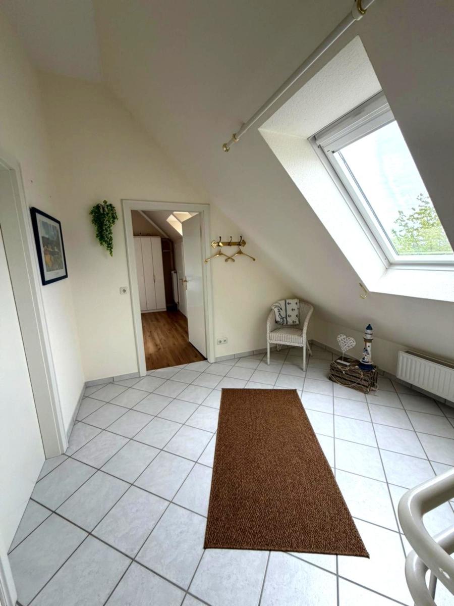 Dachgeschosszimmer mit Dachfenster, Fliesenboden und Sitzgelegenheit.