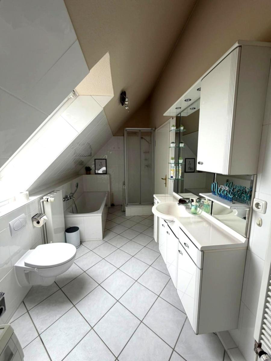 Badezimmer mit Dusche, Badewanne, Waschtisch und Toilette unter Dachschrägen.